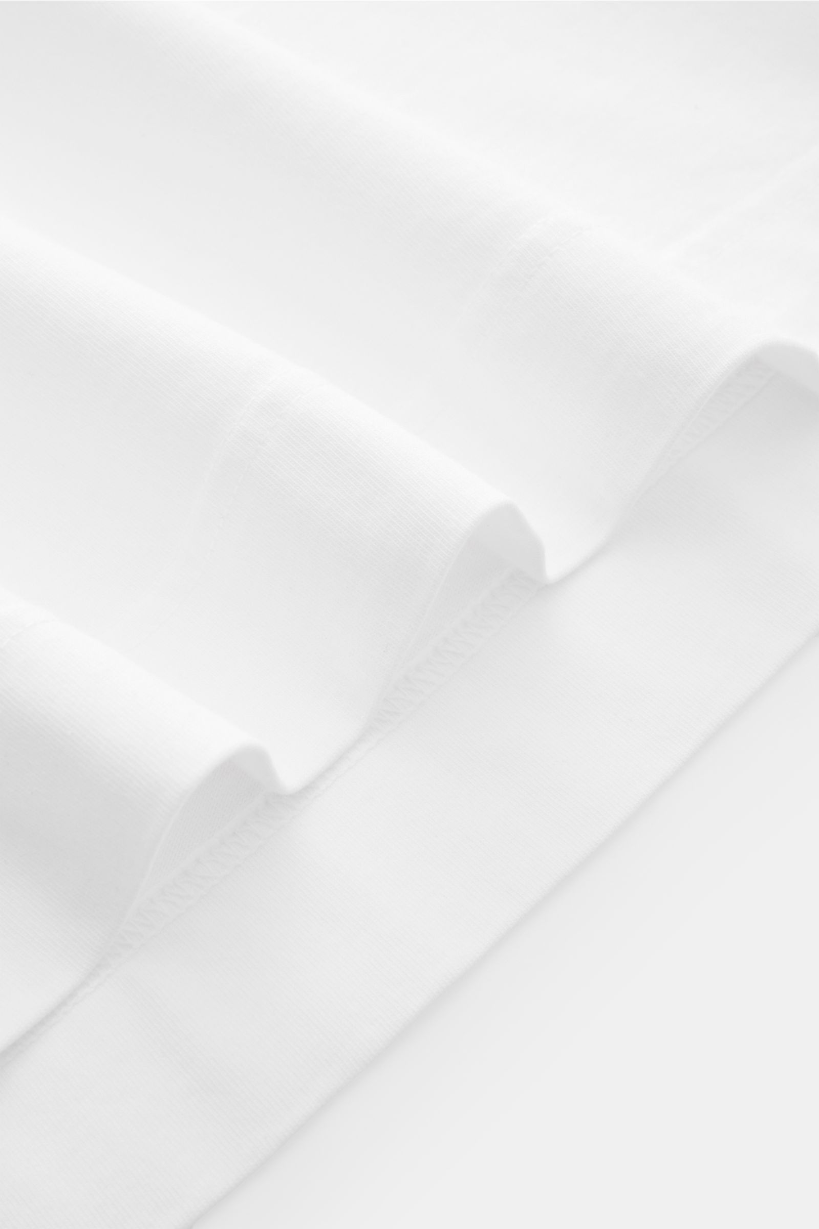 Nahaufnahme des weißen 04651/ A trip in a bag T-Shirts 'Nunu' mit weichem Griff, Rundhalsausschnitt und rückwärtigem Print, fotografiert von unten.