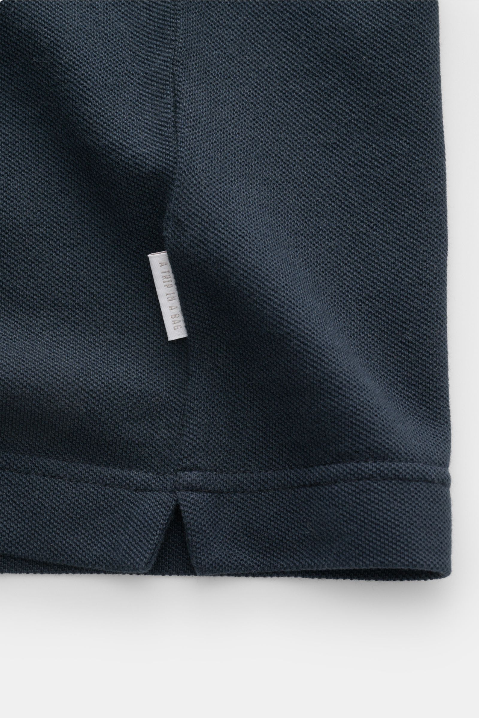 Close-up front view of the navy 04651/ A trip in a bag Piqué T-shirt showing its pure piqué cotton texture and woven side seam label.