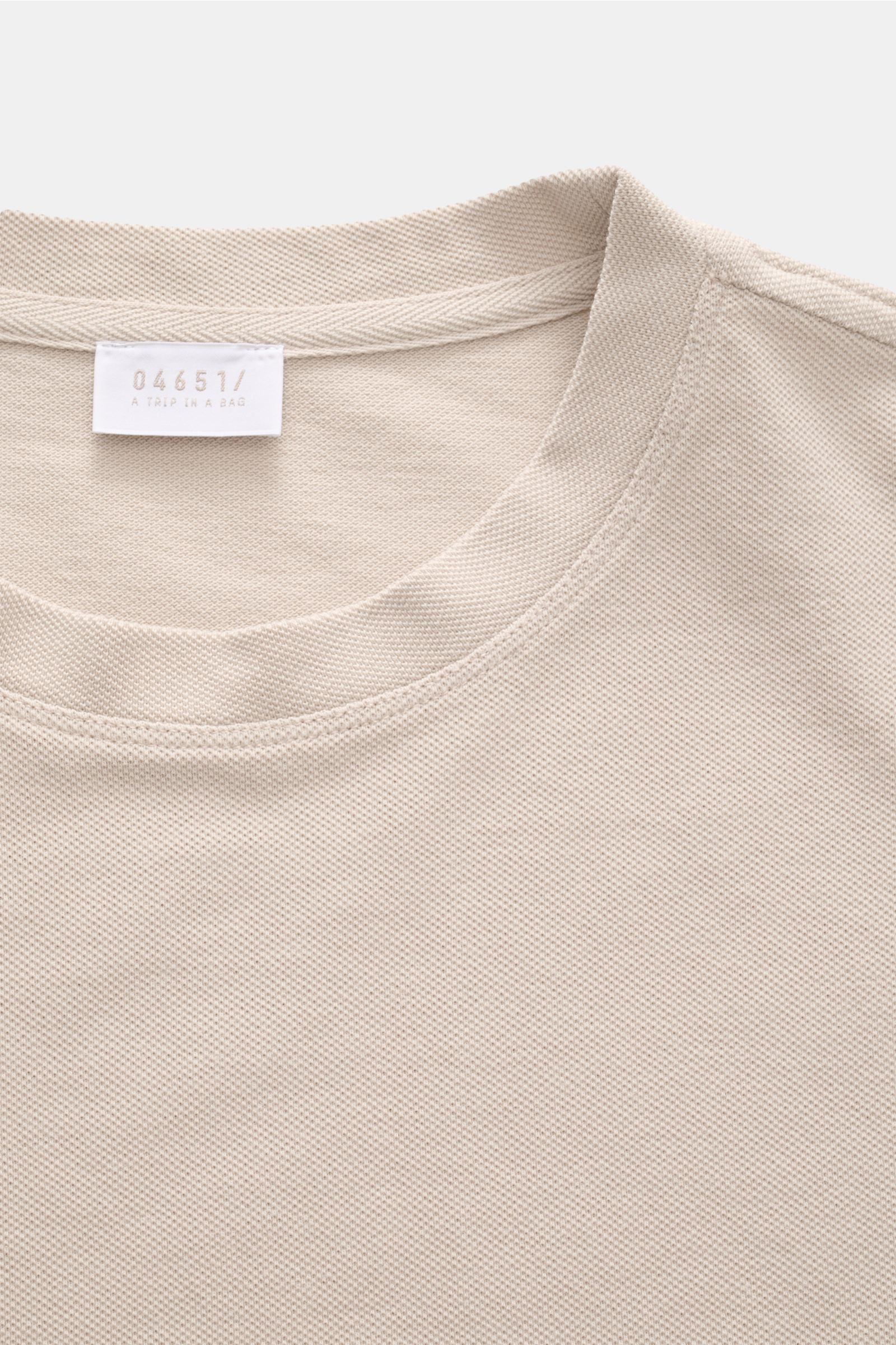 Close-up top view of the 04651/ A trip in a bag Piqué T-shirt beige showing the crew neck and woven label.

Summer essential: This piqué T-shirt from 04651/ A TRIP IN A BAG is a versatile staple that's perfect for warm days.

Pure piqué cot