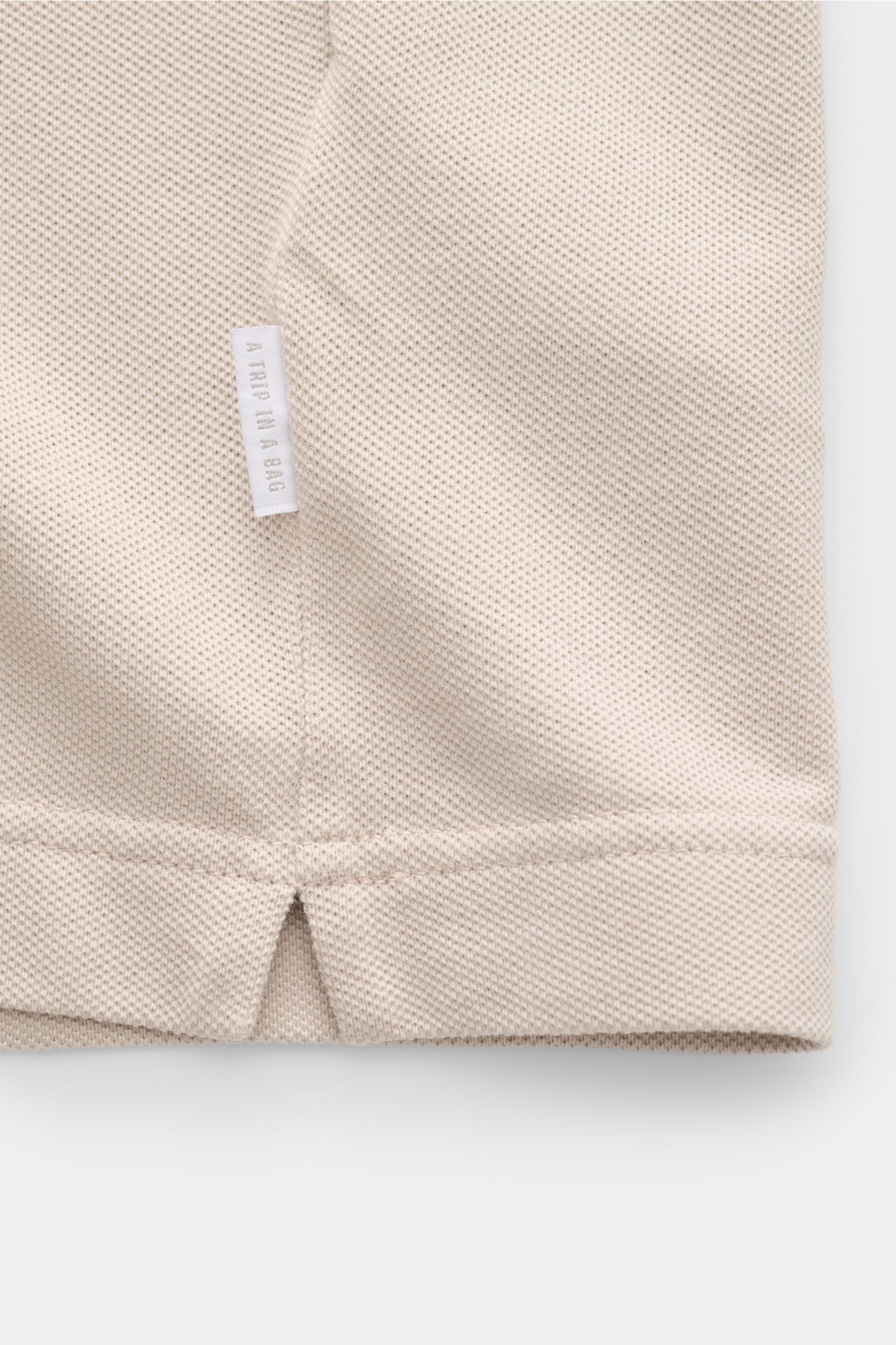 Close-up front view of the beige 04651/ A trip in a bag Piqué T-shirt showing textured pure cotton fabric and woven side label.

Summer essential: This piqué T-shirt from 04651/ A TRIP IN A BAG is a versatile staple that's perfect for warm days.
