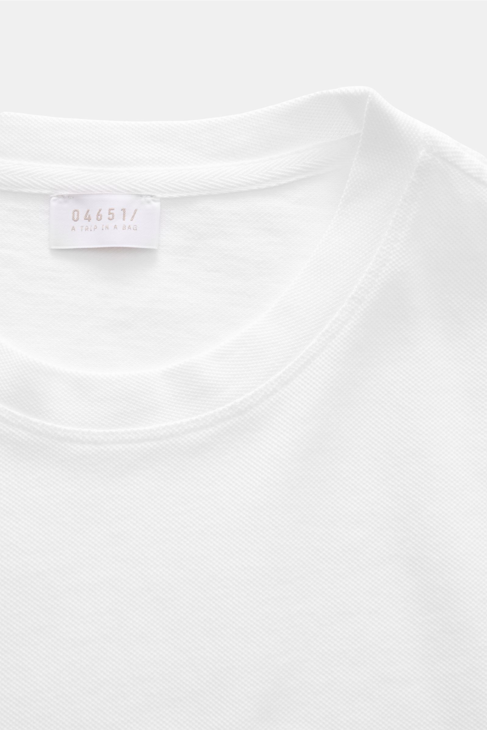 Close-up top-down view of the neckline and label of the 04651/ A trip in a bag Piqué T-shirt white, showcasing pure piqué cotton texture and ribbed bands.

Summer essential: This piqué T-shirt from 04651/ A TRIP IN A BAG is a versatile staple that's pe