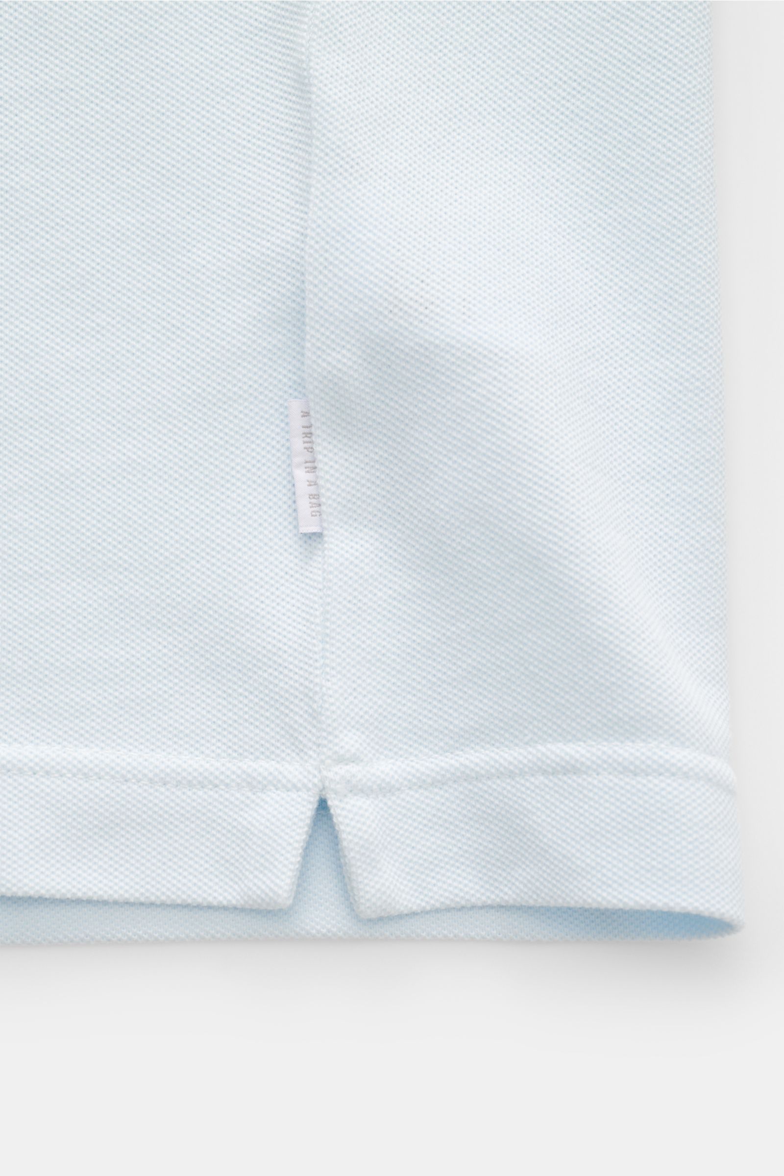 Close-up of the hem and side seam of the 04651/ A trip in a bag Piqué T-shirt pastel blue, photographed from the front.

Summer essential: This piqué T-shirt from 04651/ A TRIP IN A BAG is a versatile staple that's perfect for warm days.

P