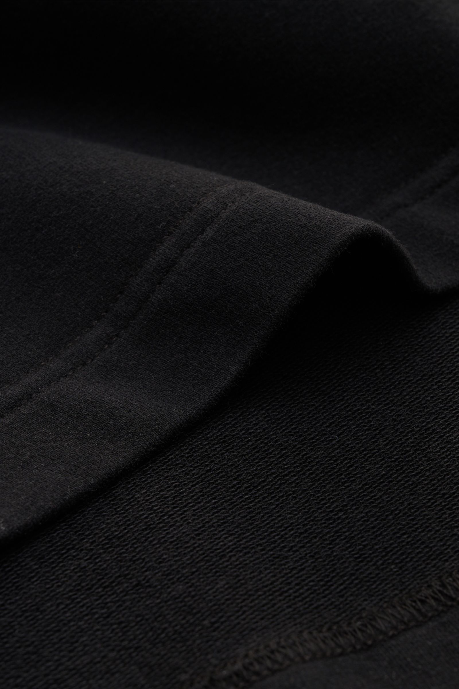 Close-up macro shot of the sleeve seam of the 04651/ A trip in a bag Crew neck T-shirt 'If Tee' black, showing fine stitching and soft elasticated cotton fabric texture. The uncomplicated cotton T-shirt 'IF Tee' by 04651/ A TRIP IN A BAG is a core basic f