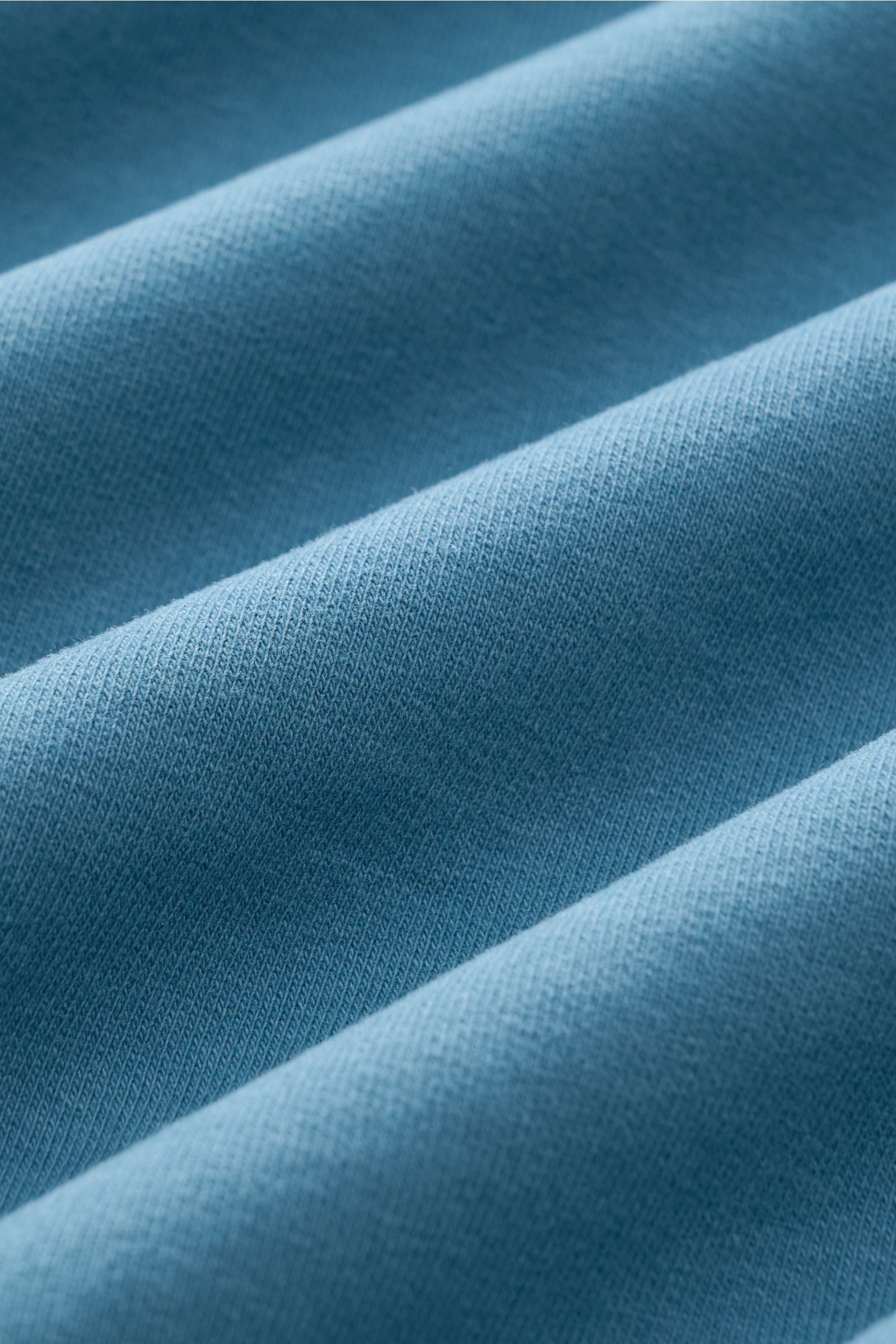 Close-up view of soft teal fabric showing fine knit texture of the 04651/ A trip in a bag Crew neck T-shirt 'If Tee' teal. The uncomplicated cotton T-shirt 'IF Tee' by 04651/ A TRIP IN A BAG is a core basic for the new season that gives a taste of a relax