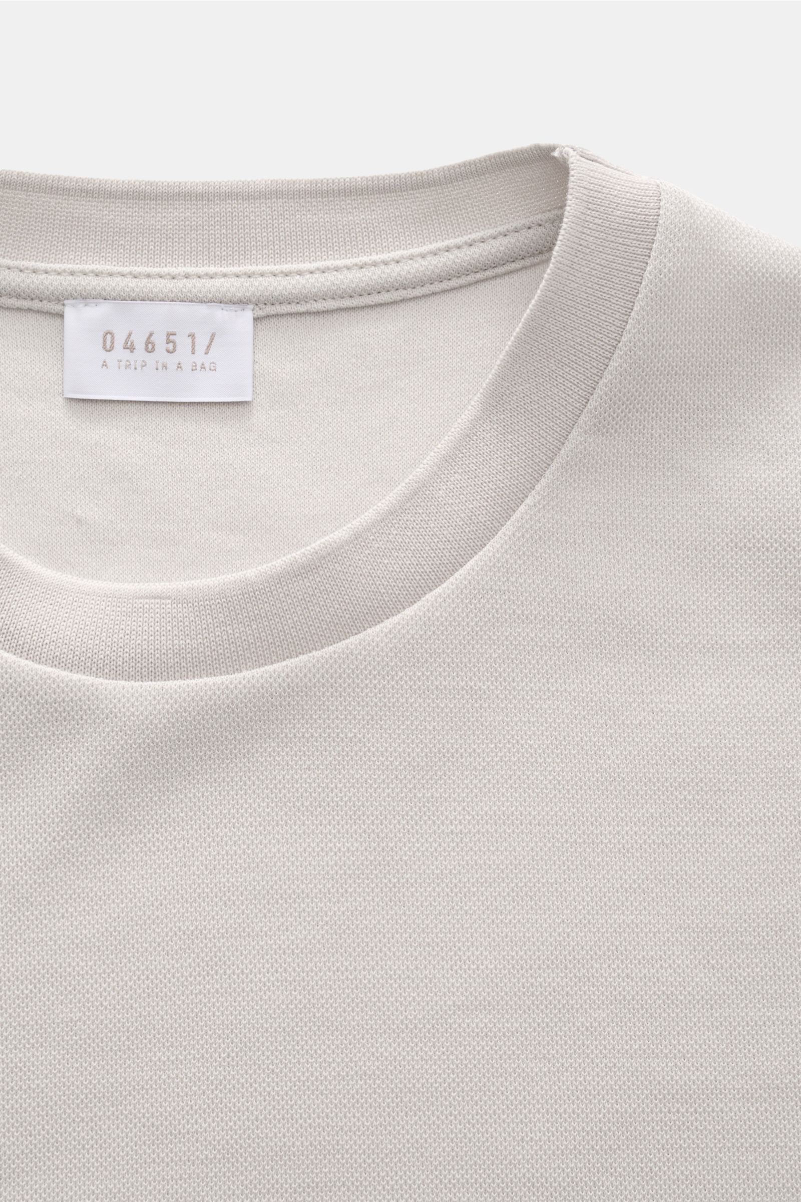 Nahaufnahme vom Rundhalsausschnitt des 04651/ A trip in a bag Piqué-T-Shirt 'TP' hellgrau aus reiner Baumwolle mit komfortablen Rippbündchen und kernigem Griff, Slim Fit, Weblabel in der Seitennaht, fotografiert von oben.