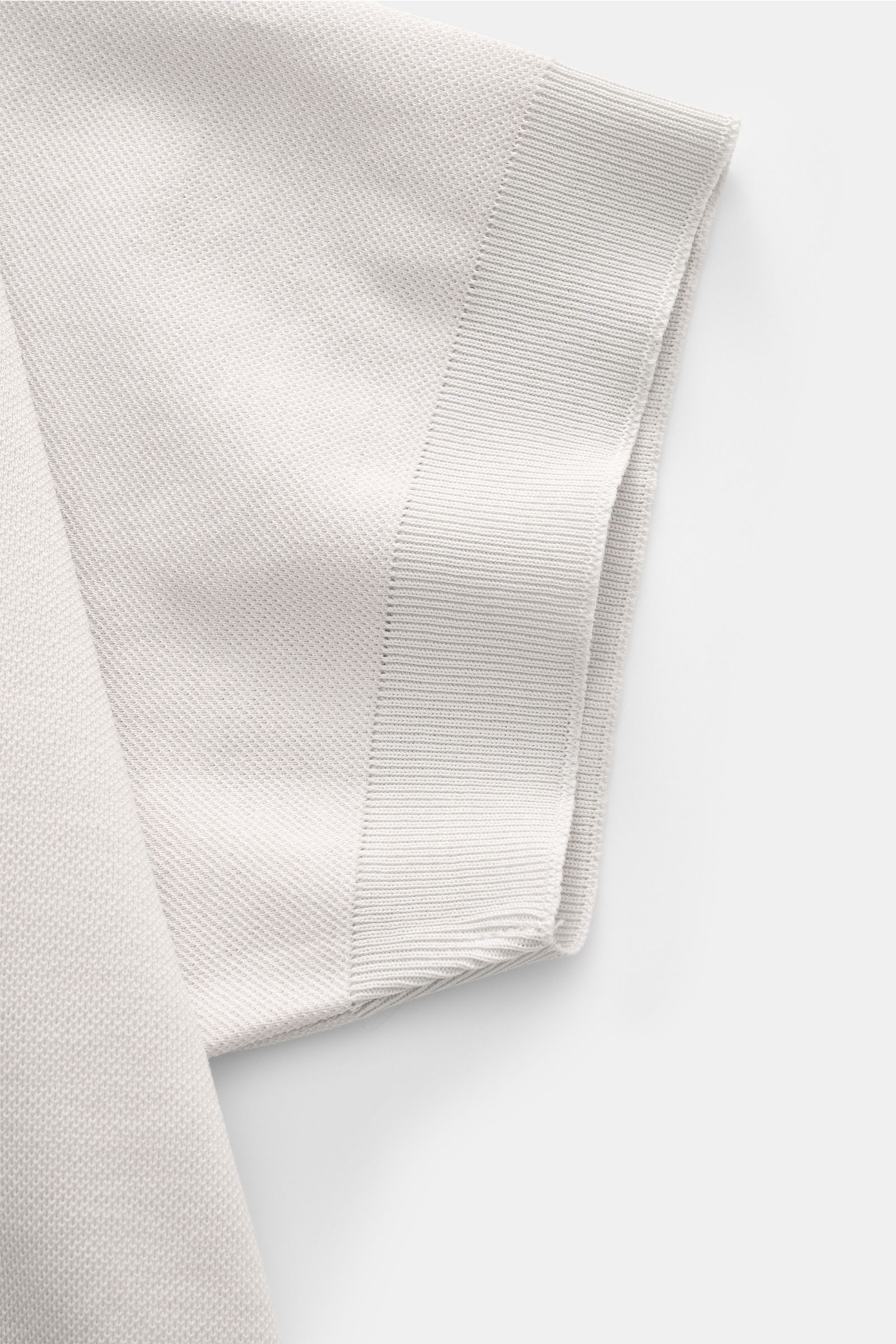 Nahaufnahme des Ärmels von 04651/ A trip in a bag Piqué-T-Shirt 'TP' hellgrau aus reiner Baumwolle, Slim Fit, mit Rundhalsausschnitt, Weblabel, Rippbündchen, kerniger Griff, von oben fotografiert.