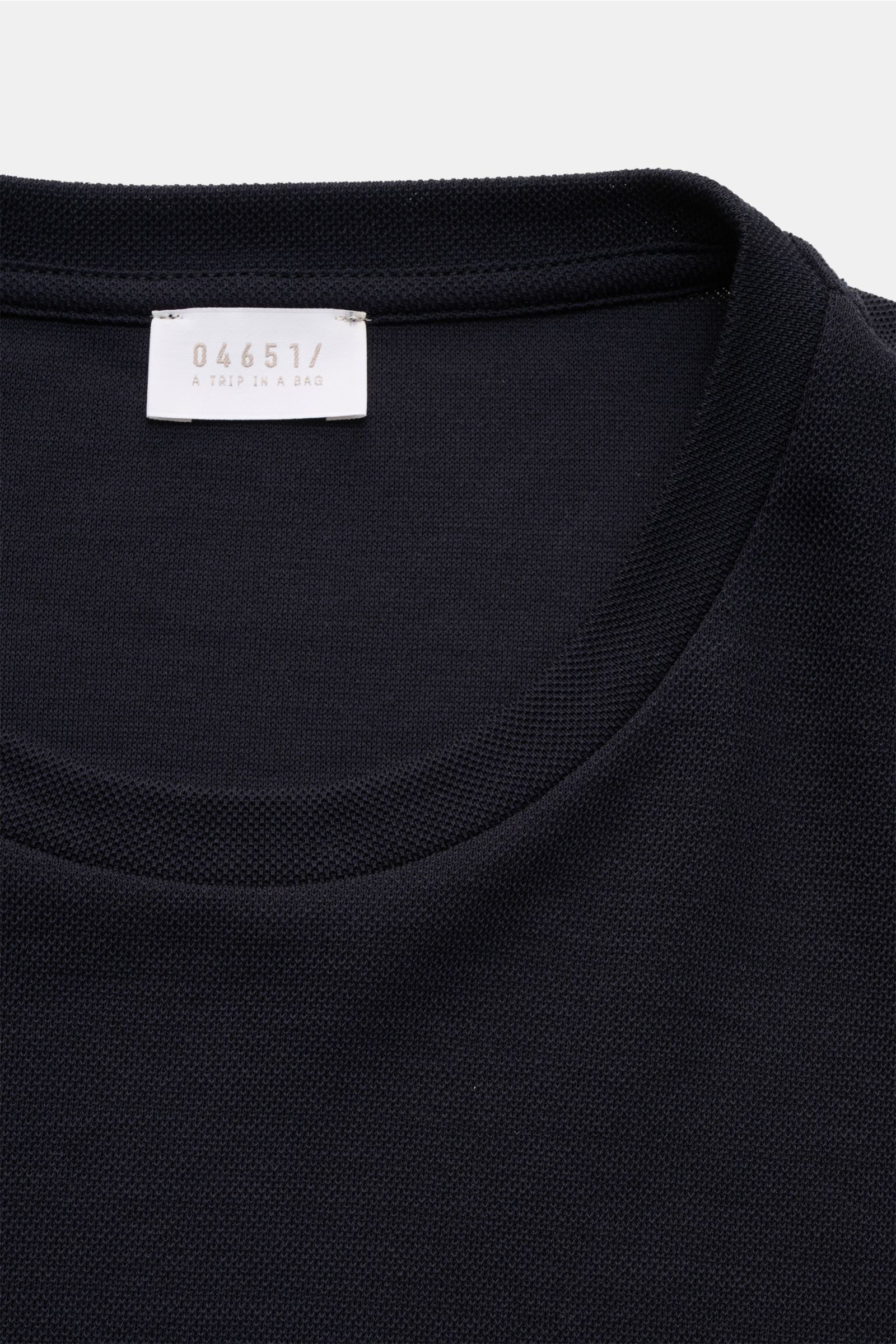 Close-up front view of the neckline and label of the 04651/ A trip in a bag Piqué-T-Shirt 'TP' navy, made of pure cotton piqué with a grainy texture.

Additional description:
Summer Essential: Das Piqué-T-Shirt von 04651/ A TRIP IN A BAG überzeugt an w
