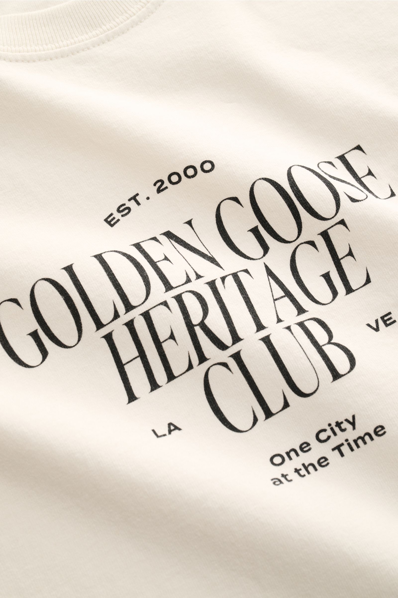 Close-up front view of Golden Goose Rundhals-T-Shirt creme showing black logo print on cream cotton fabric.

Urbaner Eyecatcher: Das T-Shirt von GOLDEN GOOSE ergänzt Sommerlooks mit markantem Print und unverwechselbarer Lässigkeit.

reine B