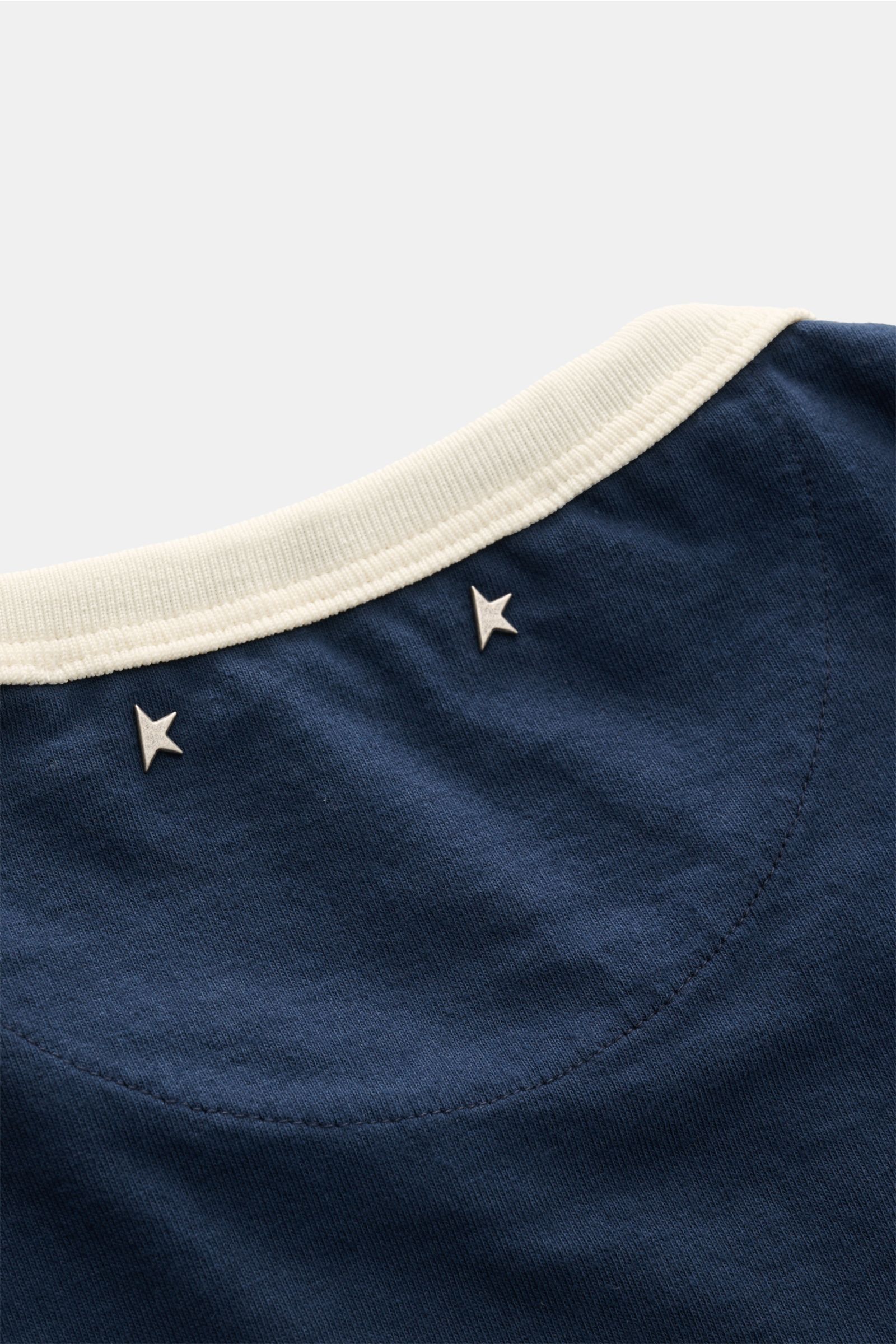 Golden Goose Rundhals-T-Shirt navy/creme close-up from above shows navy fabric with cream ribbed collar and silver star studs on back neck.

Retro-Sportswear neu interpretiert: Das T-Shirt von GOLDEN GOOSE sorgt mit markantem Print für legere Sommerloo