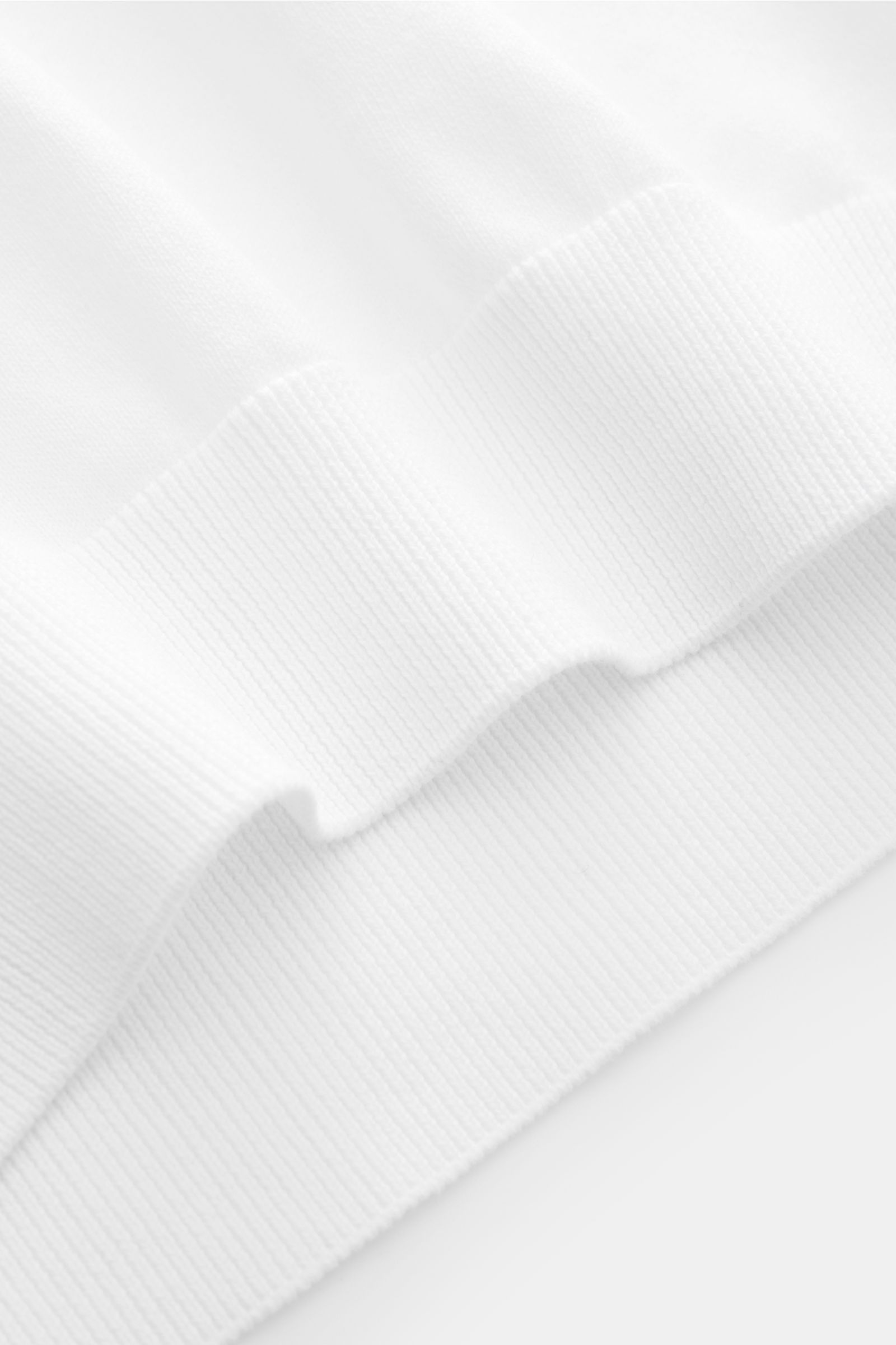 Close-up, angled view of the ribbed hem of the 04651/ A trip in a bag Kurzarmpullover 'Pima Cotton' weiß made from fine, soft Pima cotton knit.

Aus feiner Pima-Baumwolle gefertigt, lässt Sie der Kurzarmpullover 'Pima Cotton' von 04651 / A TRIP IN A BA