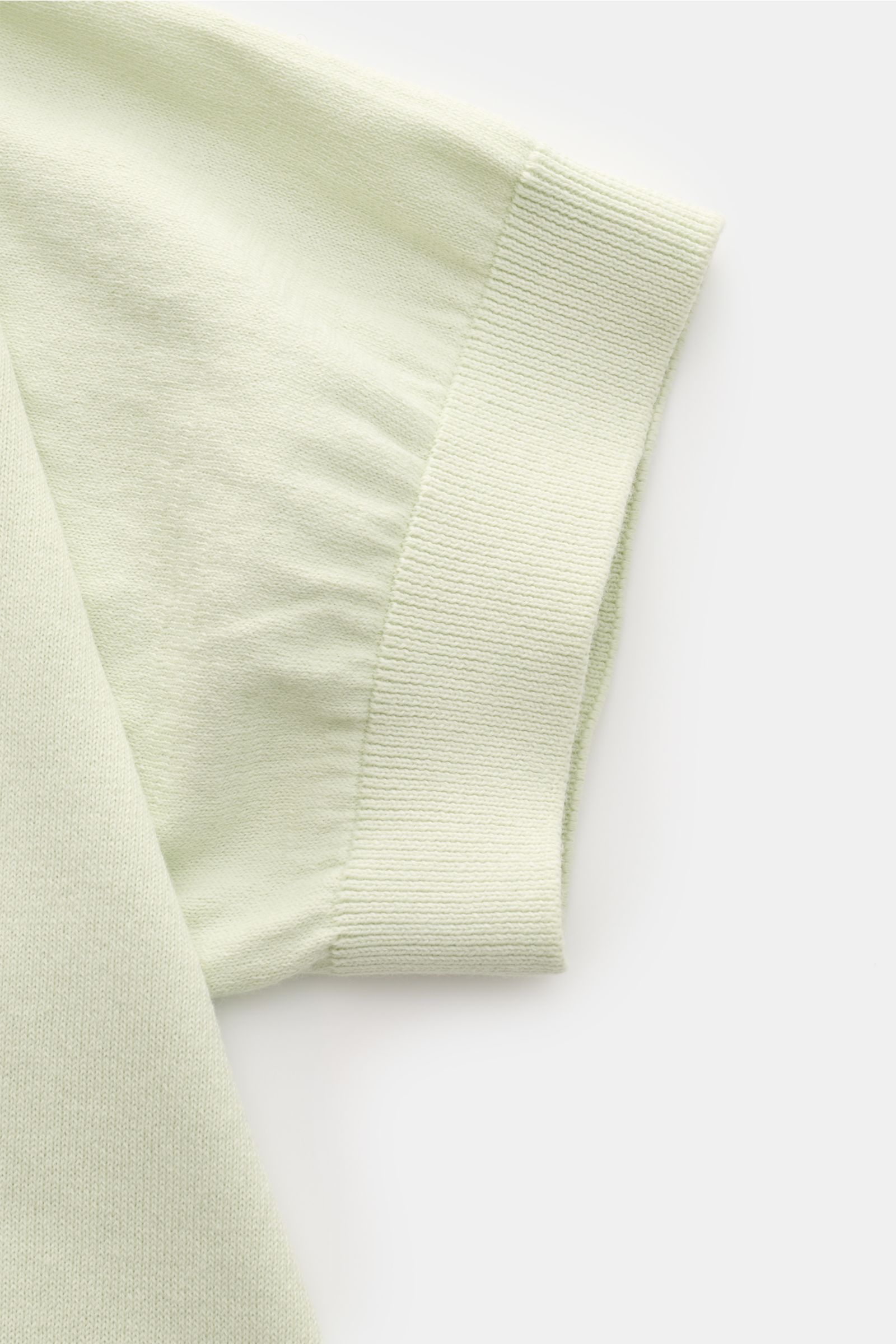 Close-up view of the sleeve cuff of the 04651/ A trip in a bag Kurzarmpullover 'Pima Cotton' pastellgrün, made from fine Pima cotton with a soft feel, very fine knit, slim fit, round neckline, and flexible ribbed cuffs, shown from a top angle.
