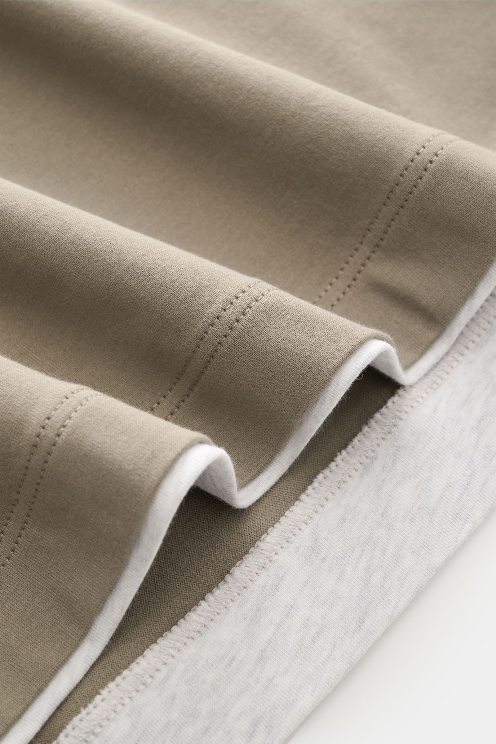 Close-up side view of folded Brunello Cucinelli Rundhals-T-Shirt taupe/grau meliert showing soft cotton jersey fabric and color-contrasted double hems.

Description: BRUNELLO CUCINELLI liefert mit diesem legeren T-Shirt aus angenehmer Baumwolle ein unv