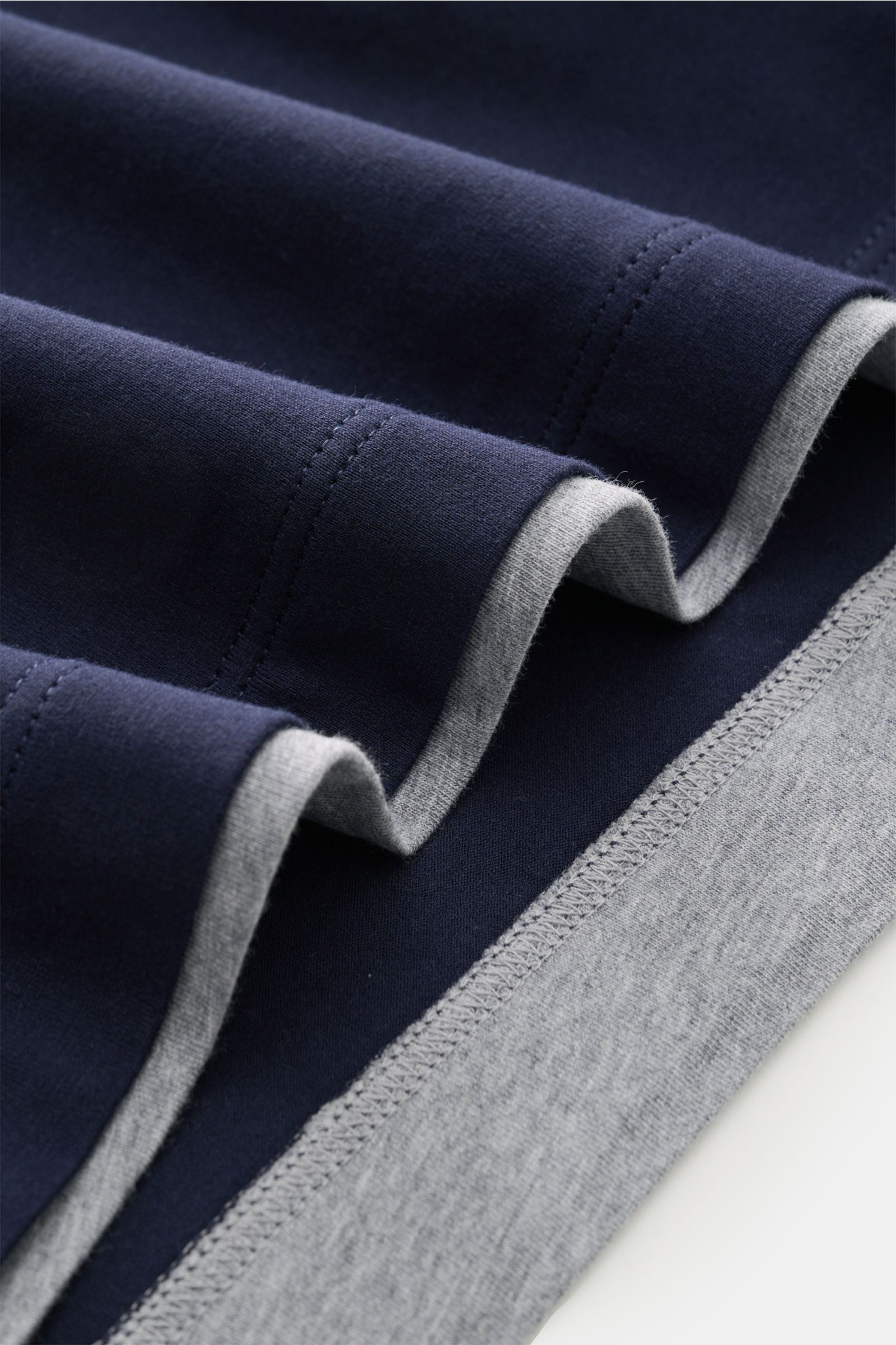 Close-up side view of folded Brunello Cucinelli Rundhals-T-Shirt navy/grau meliert showing soft cotton jersey and contrast double hems.

BRUNELLO CUCINELLI liefert mit diesem legeren T-Shirt aus angenehmer Baumwolle ein unverzichtbares Basic für Ihre C