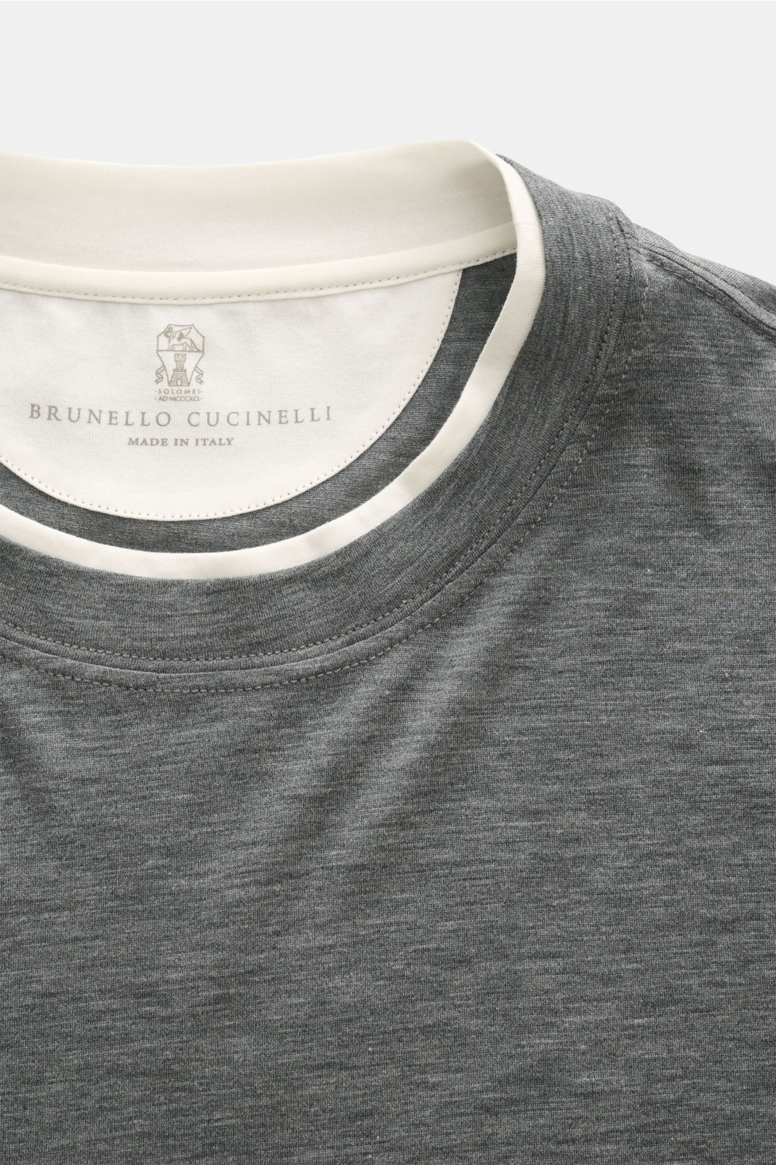 Close-up front view of Brunello Cucinelli Rundhals-T-Shirt dunkelgrau meliert/creme showing the round neckline with contrast double hem.

BRUNELLO CUCINELLI liefert mit diesem legeren T-Shirt aus luxuriöser Seiden-Baumwollmischung ein unverzichtbares B