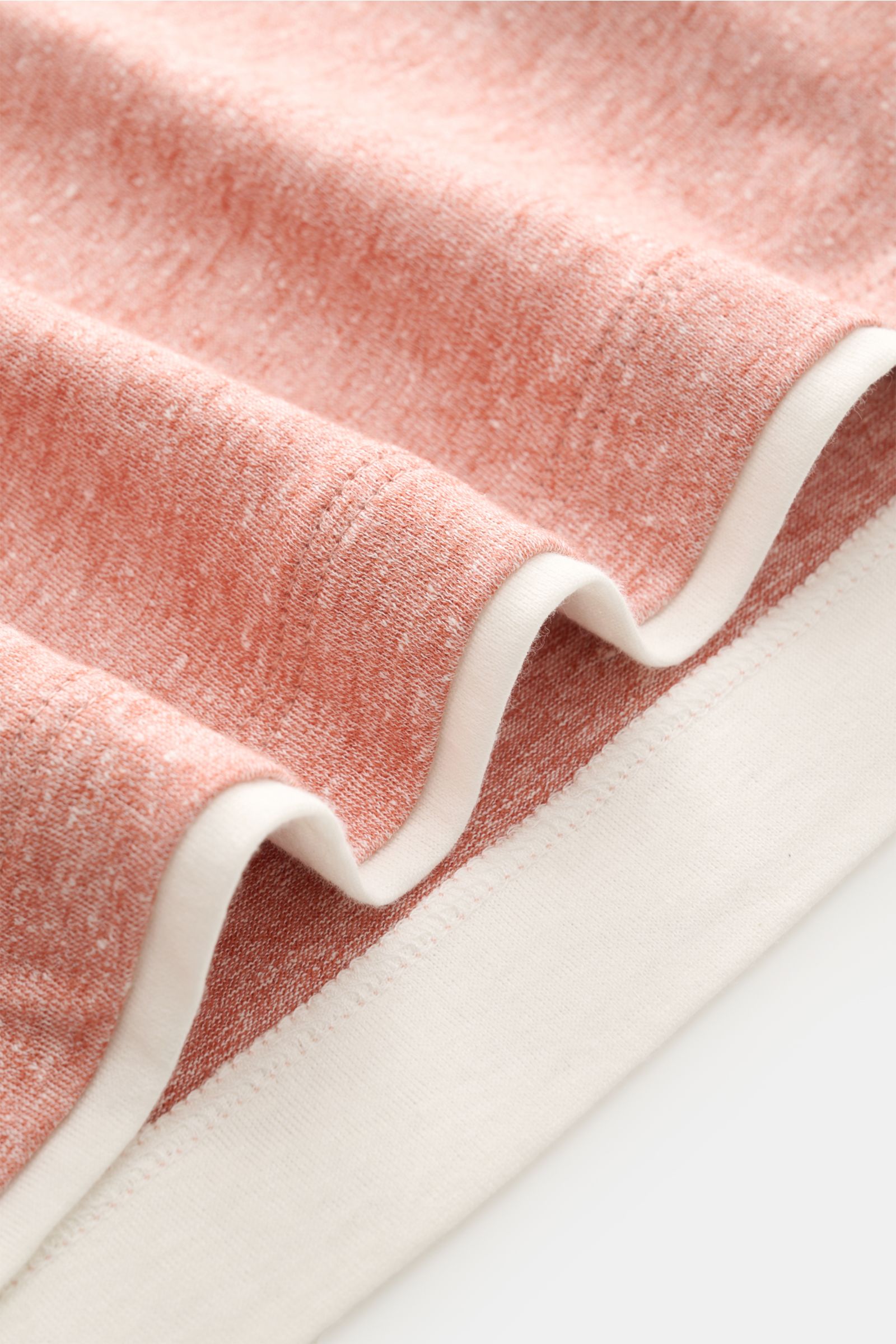 Close-up view of folded Brunello Cucinelli Rundhals-T-Shirt hellrot meliert/creme showing soft linen-cotton fabric with contrasting double hems.

BRUNELLO CUCINELLI liefert mit diesem komfortablen T-Shirt aus luxuriöser Leinen-Baumwollmischung ein unve