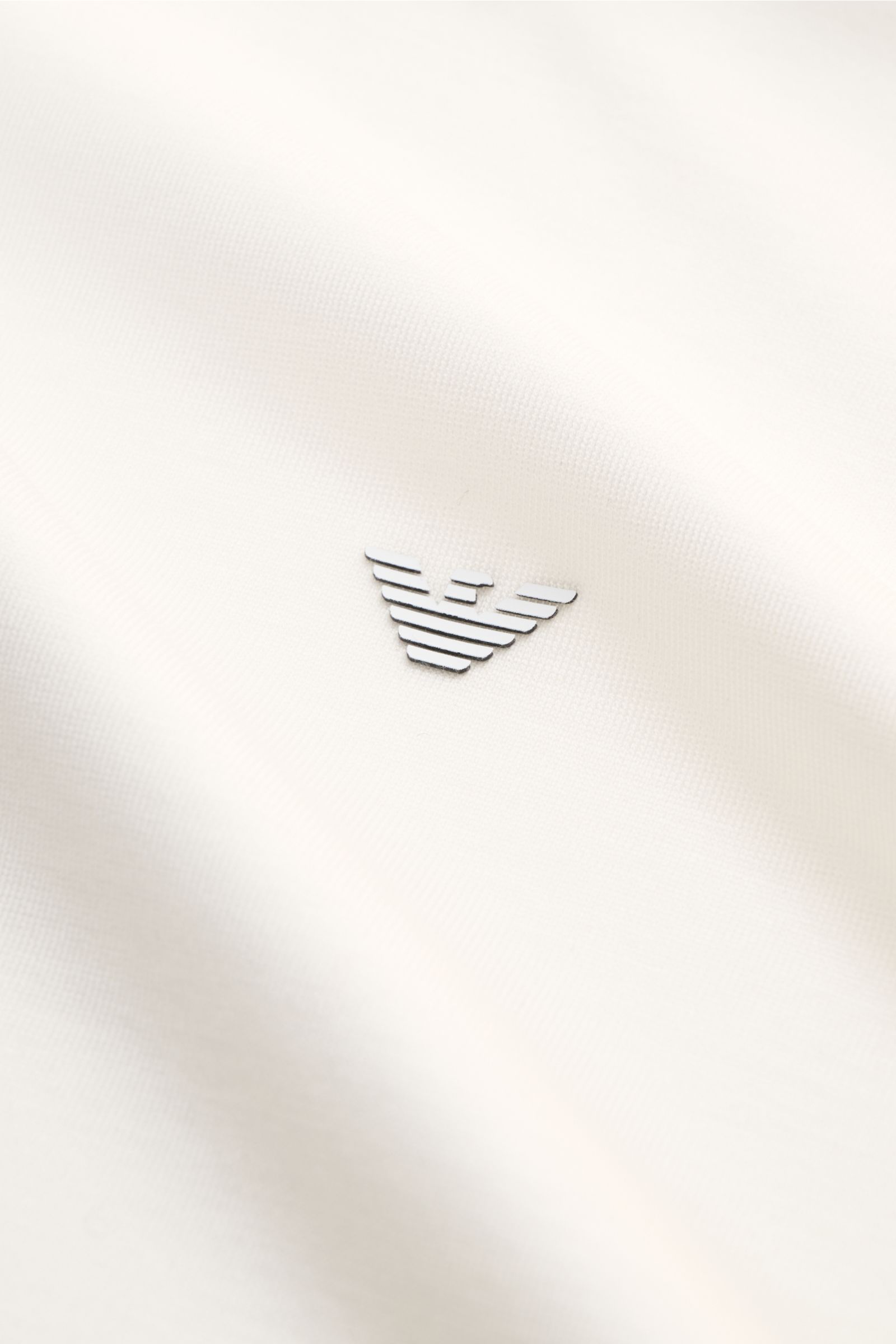 Emporio Armani Rundhals-T-Shirt offwhite aus glattem Jersey mit gummiertem Logo, Nahaufnahme der Front in schräger Perspektive.
