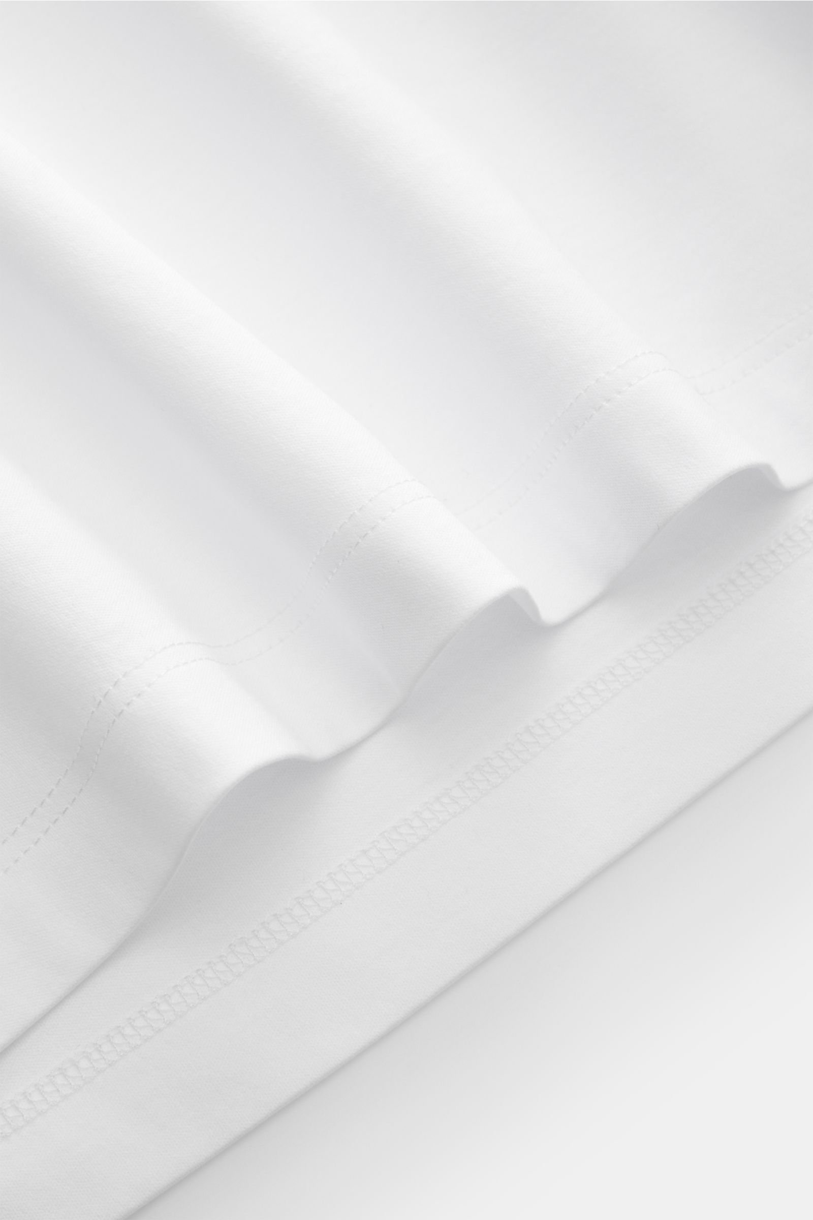 Brunello Cucinelli Rundhals-Longsleeve weiß, Detailaufnahme vom Saum, weicher Jersey aus reiner Baumwolle, Slim Fit, kurze Saumschlitze, leichte Qualität.
