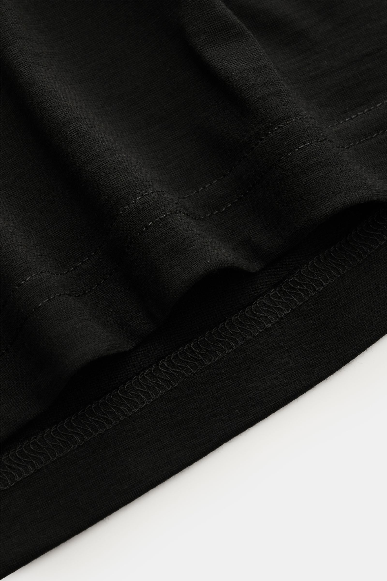 Close-up of the hem stitching on Stefan Brandt Merino crew neck long sleeve 'Enno' black, showing fine jersey fabric and smooth texture.

Description: With the long sleeve 'Enno' in super fine merino wool, STEFAN BRANDT presents a timeless essential fo