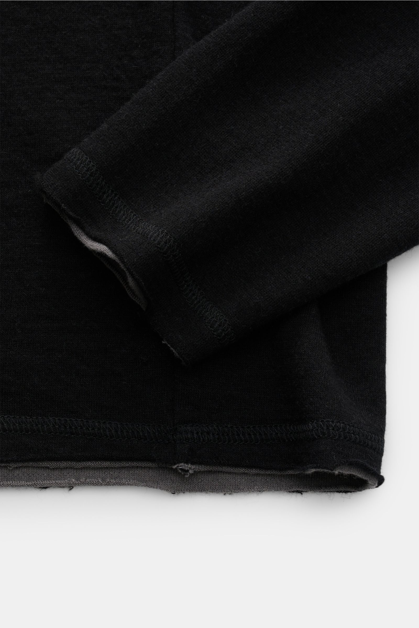 Nahaufnahme des schwarzen Kiefermann Longsleeve 'Jeldrik' mit offenem Saum und Ärmelkanten, weicher Jersey-Mix aus Baumwolle und Cashmere.