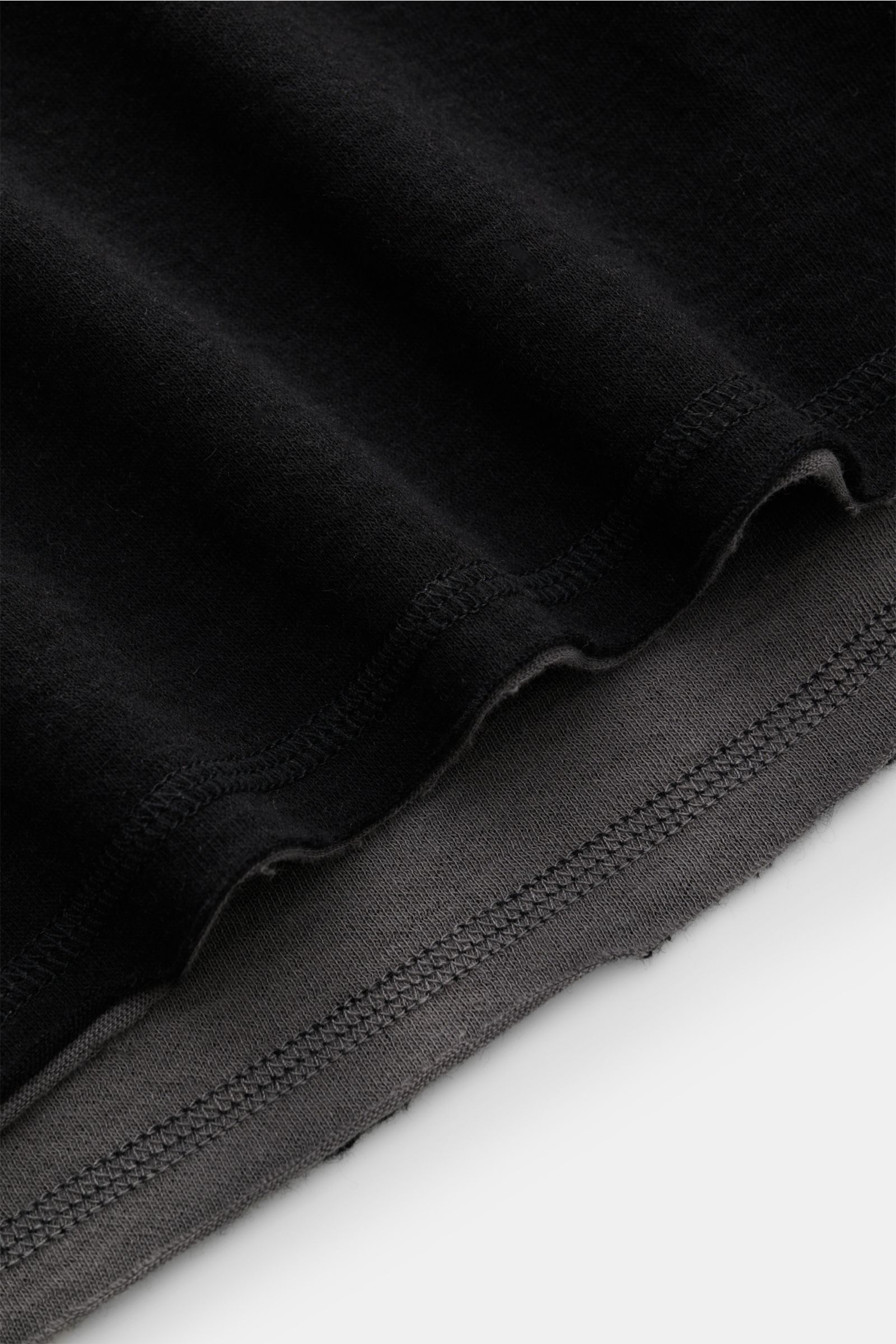 Nahaufnahme der offenen Saum- und Ärmelkanten des Kiefermann Longsleeve 'Jeldrik' schwarz aus Baumwolle und Cashmere, weicher Griff, Regular Fit, Rundhalsausschnitt, fotografiert von schräg oben.