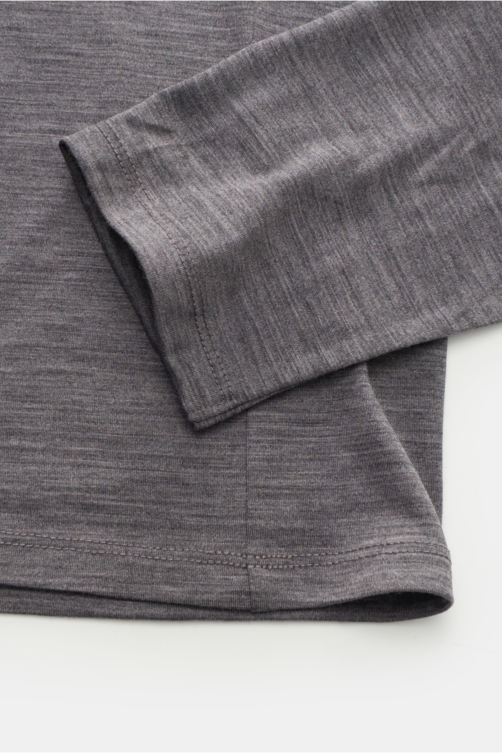 The Product is the Hero Merino Longsleeve dunkelgrau meliert, Nahaufnahme von Ärmel und Saum, pure Merinowolle, weich, Slim Fit, Rundhalsausschnitt, atmungsaktiv, wärmeregulierend.