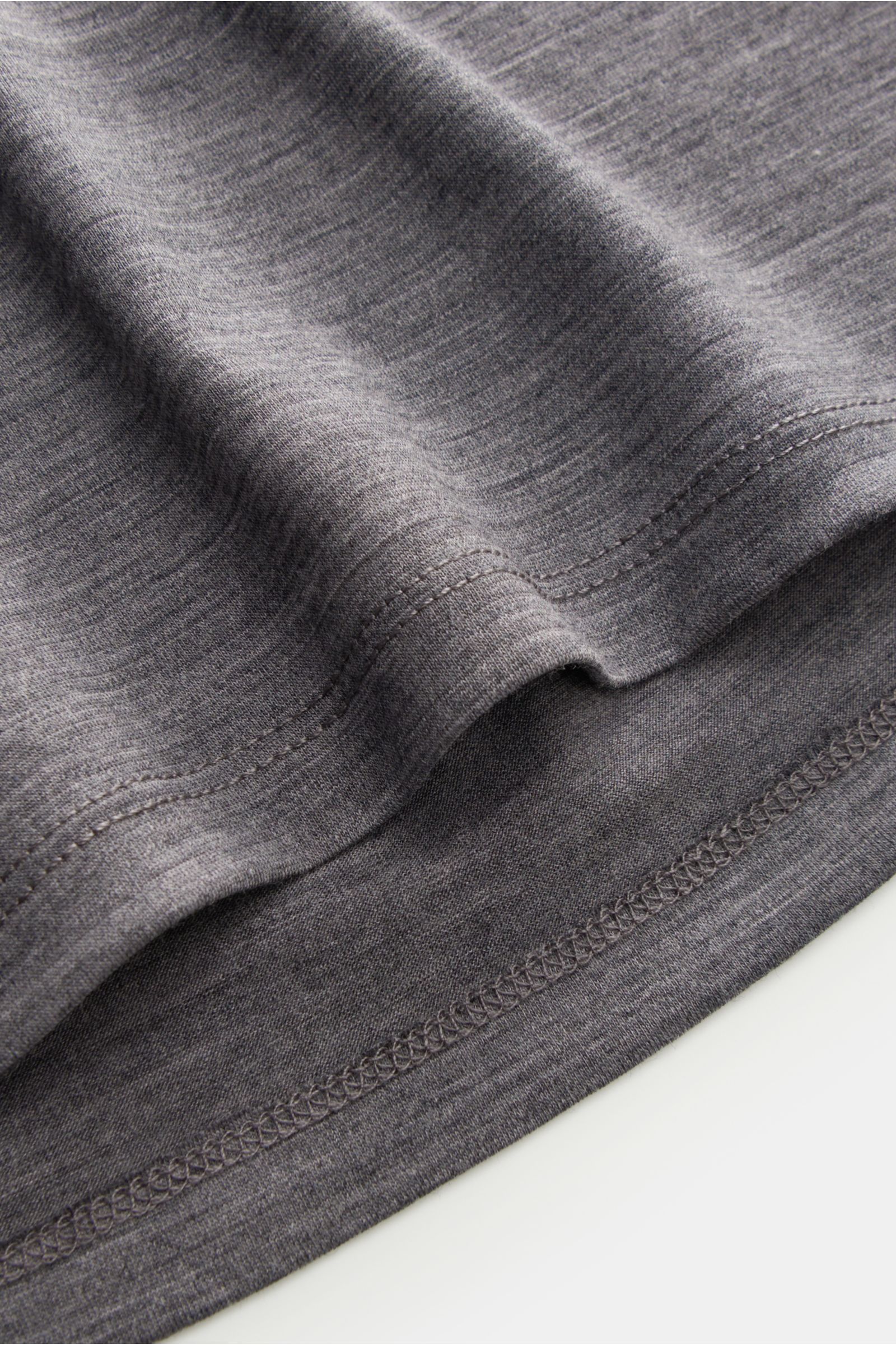 The Product is the Hero Merino Longsleeve dunkelgrau meliert in Nahaufnahme von der Saumkante, aus leichter, supersofter reiner Merinowolle, Slim Fit, Rundhalsausschnitt.