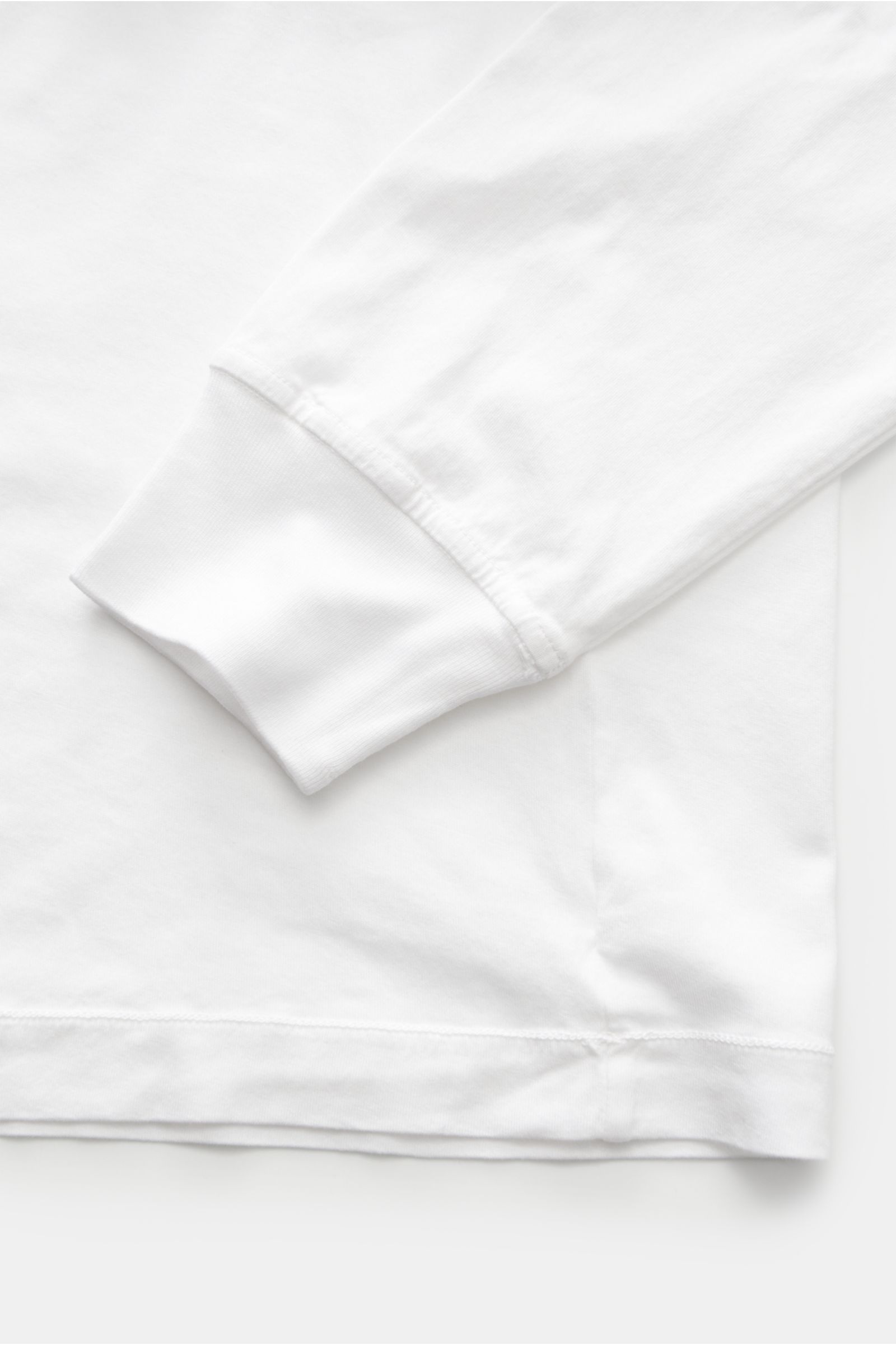 Stone Island Rundhals-Longsleeve weiß, Nahaufnahme von Ärmel und Saum, weicher Baumwolljersey, Slim Fit, Rippbündchen, Weblabel sichtbar.