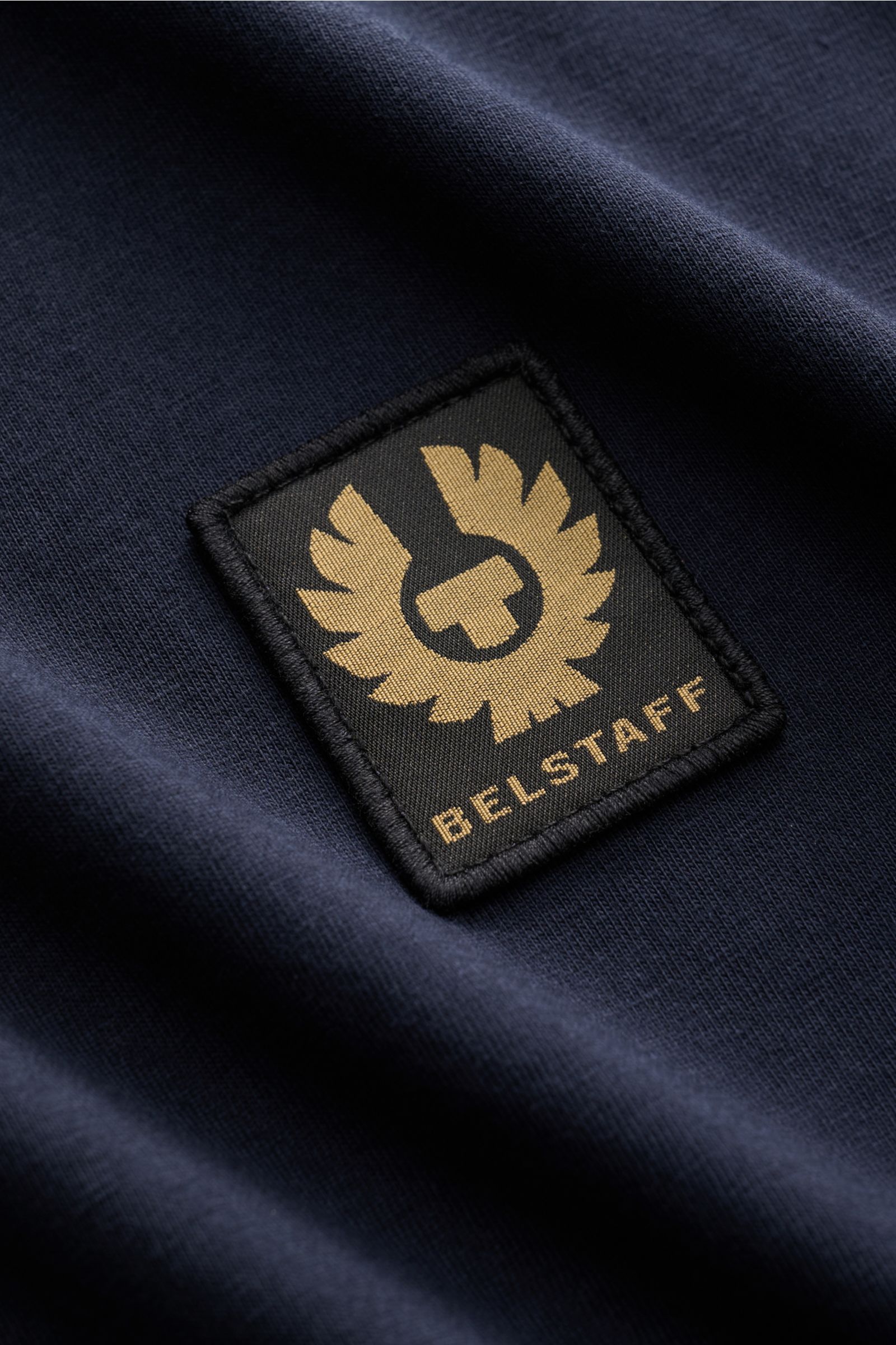 Nahaufnahme des Belstaff Rundhals-Longsleeve navy aus leichtem Baumwolljersey mit BELSTAFF-Weblabel auf der Brust, Slim Fit und Rundhalsausschnitt.