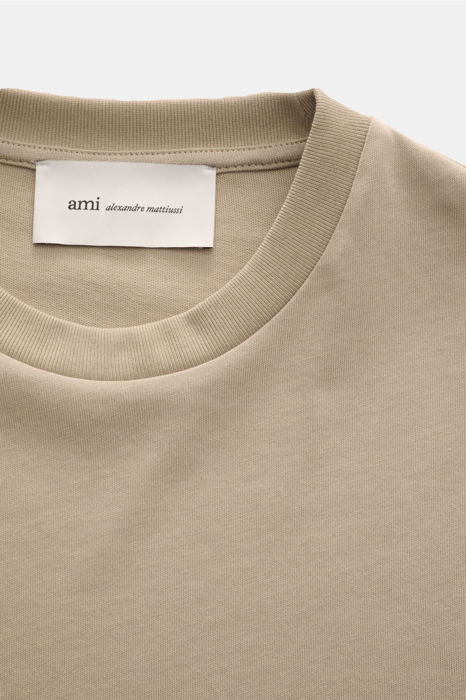 Close-up front view of Ami Paris Long sleeve taupe showing the crew neck and label with ami alexandre mattiussi branding.

Create perfect urban looks with this long sleeve by AMI PARIS – the quilted seams and signature heart logo on the hem make it an 