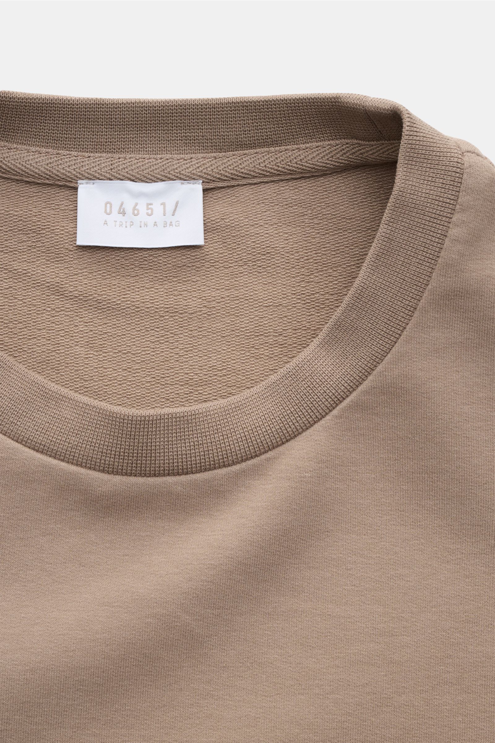 Nahaufnahme des Rundhalsausschnitts des taupefarbenen 04651/ A trip in a bag Rundhals-Longsleeve 'If Tee' aus elastischer Baumwolle mit Weblabel, weichem Griff und Oversized Fit.