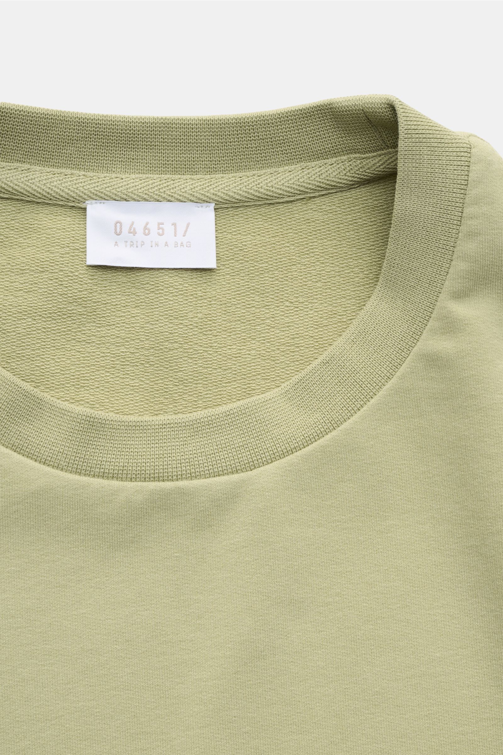 Nahaufnahme des Rundhalsausschnitts vom 04651/ A trip in a bag Rundhals-Longsleeve 'If Tee' salbei aus elastischer Baumwolle mit Weblabel in der Seitennaht.