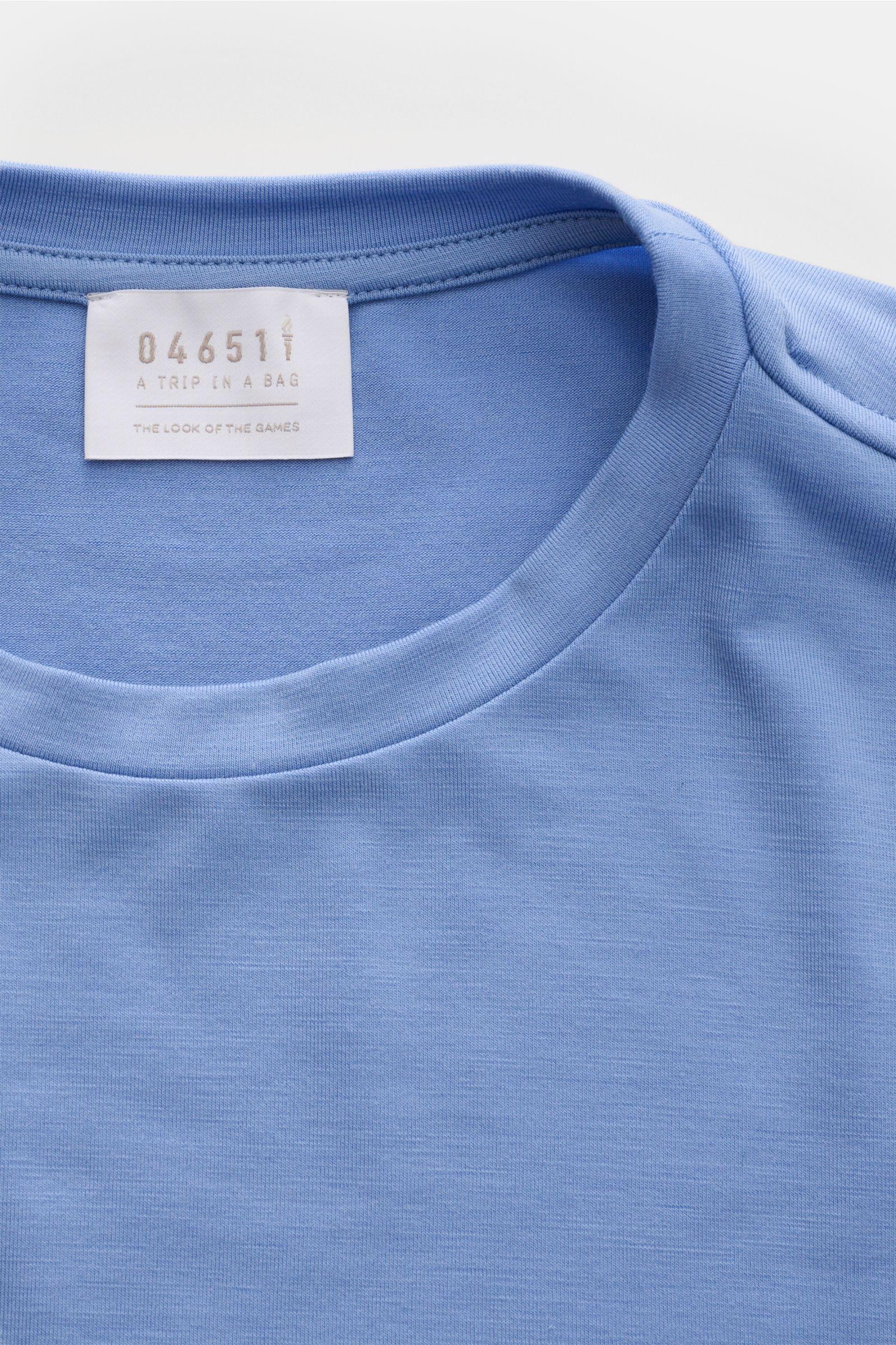 Close-up front view of the 04651/ A trip in a bag Merino Longsleeve rauchblau showing its round neckline and fabric texture. Vielseitiges Basic: Das Merino Longsleeve aus der 'Look of the Games' Capsule von 04651/ A TRIP IN A BAG, inspiriert von den Olymp