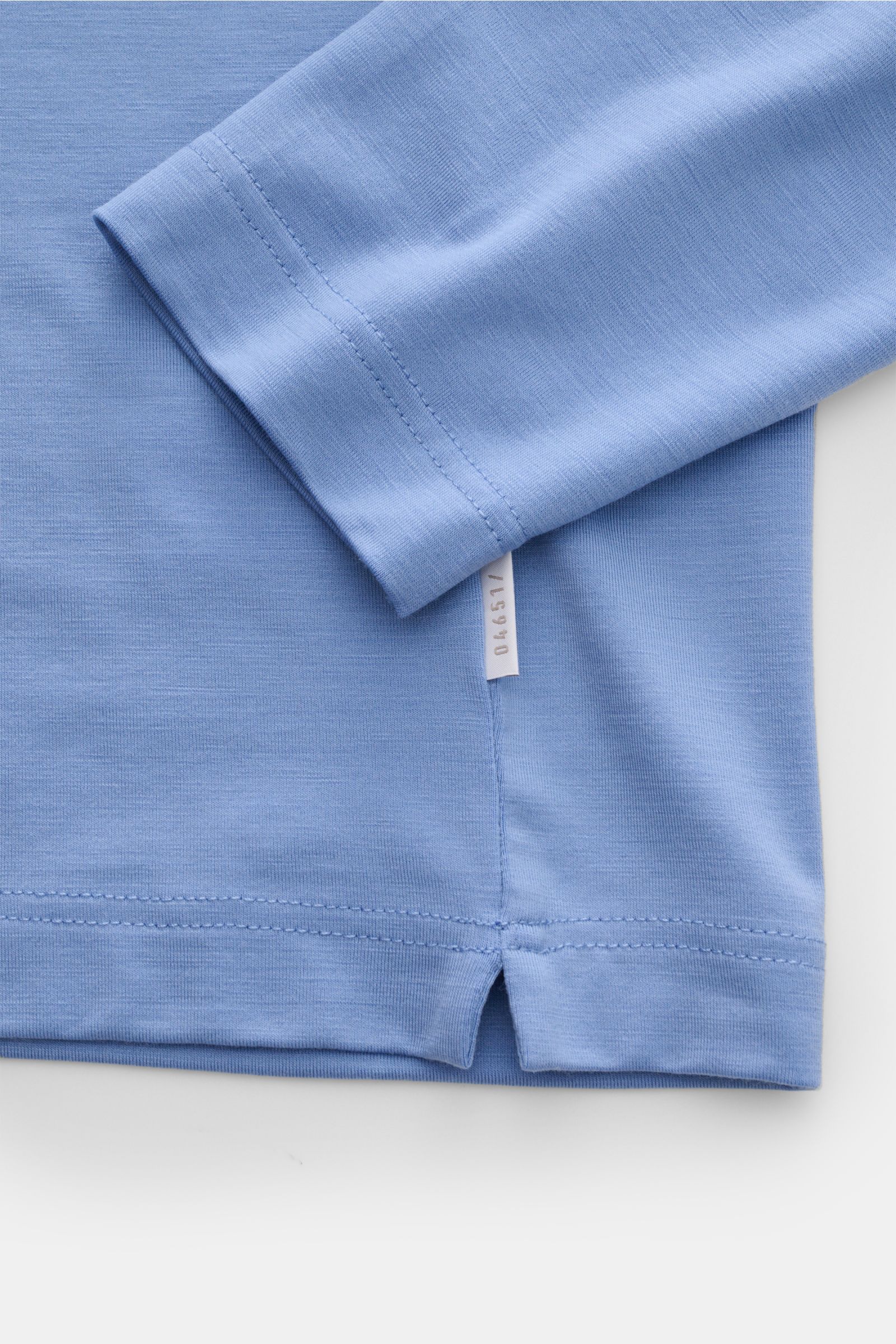 Close-up of 04651/ A trip in a bag Merino Longsleeve rauchblau showing sleeve and hem with short side slits, photographed from above. Vielseitiges Basic: Das Merino Longsleeve aus der 'Look of the Games' Capsule von 04651/ A TRIP IN A BAG, inspiriert von 