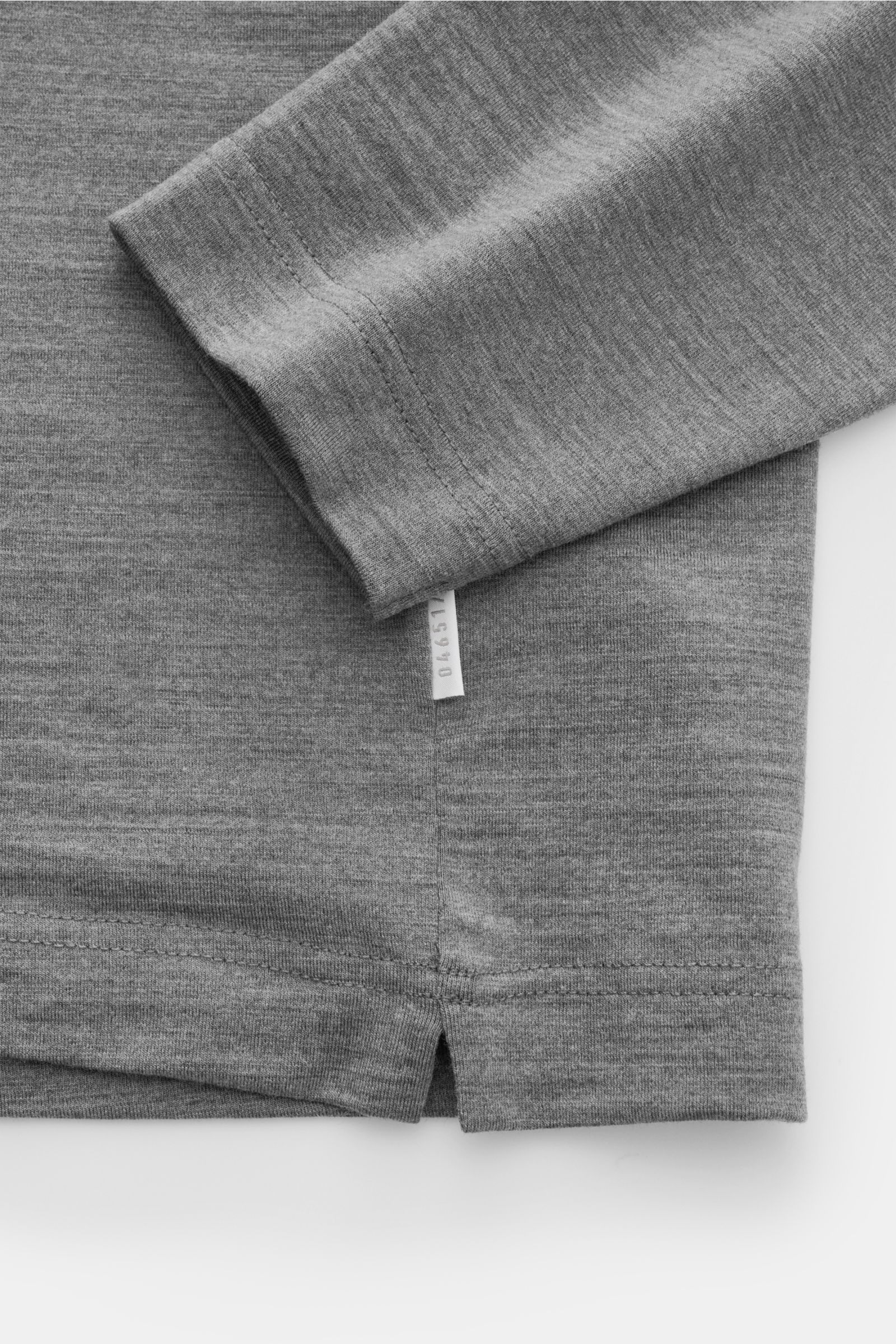 04651/ A trip in a bag Merino Longsleeve dunkelgrau meliert, Detailaufnahme von Saum und Ärmel mit kurzen Saumschlitzen, elastisch, weich, Regular Fit.