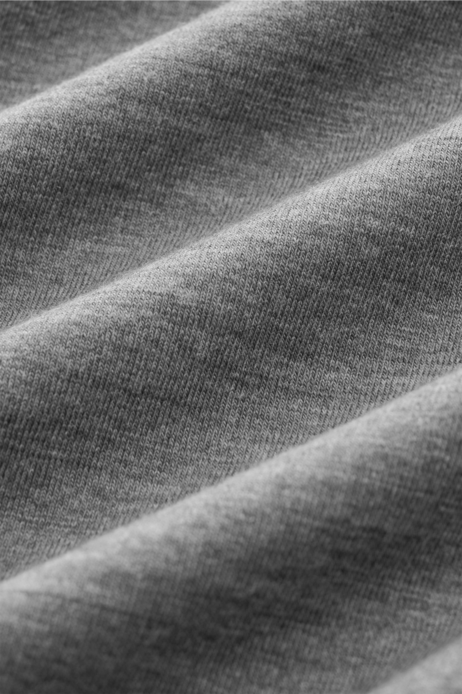 Detailaufnahme des elastischen, weichgriffigen Stoffes des dunkelgrau melierten 04651/ A trip in a bag Merino Longsleeves aus nächster Nähe.
