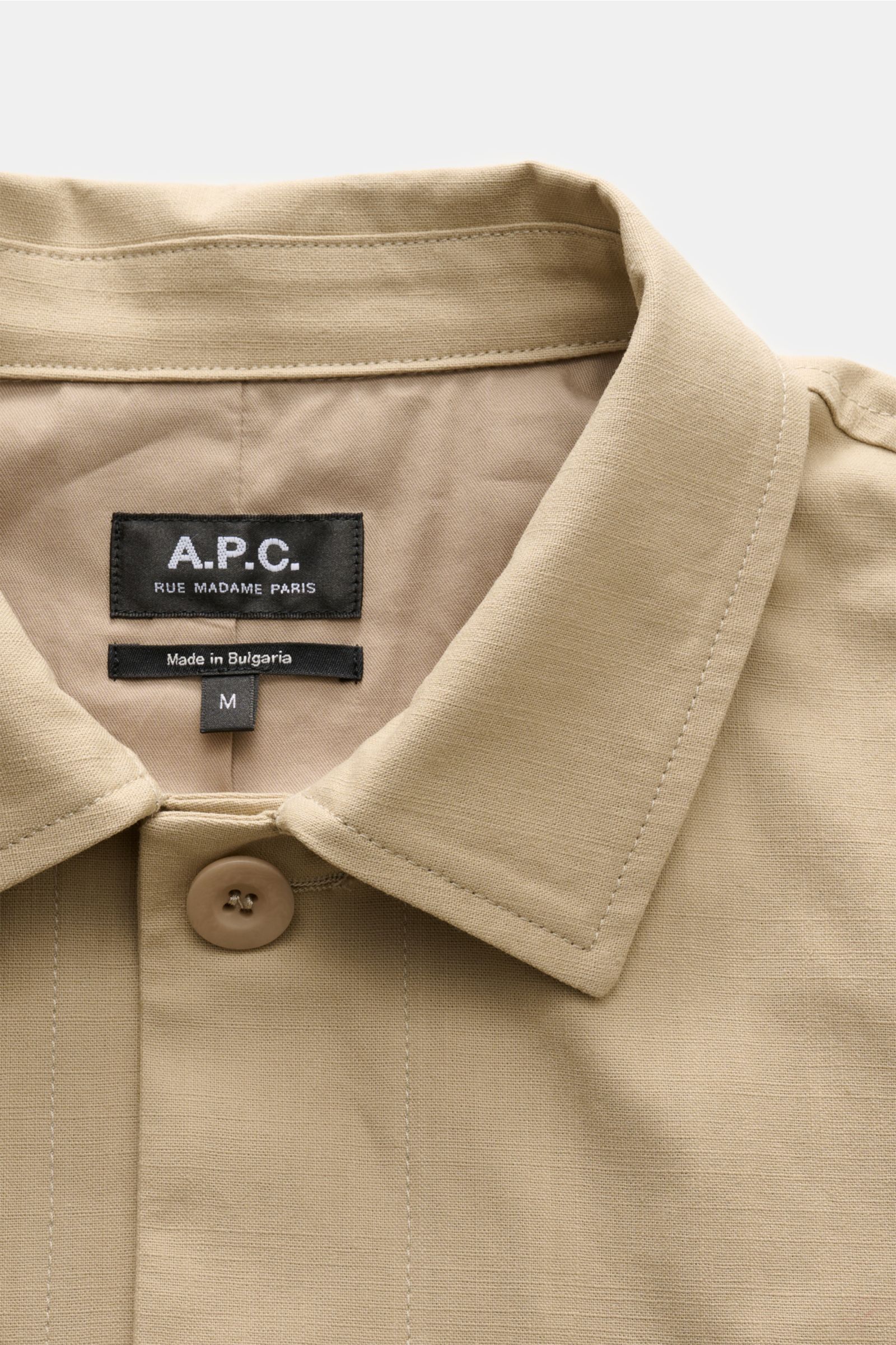 A.P.C. Overshirt 'Rodney' in beige, close-up of collar and button, showcasing robust pure cotton fabric and label.