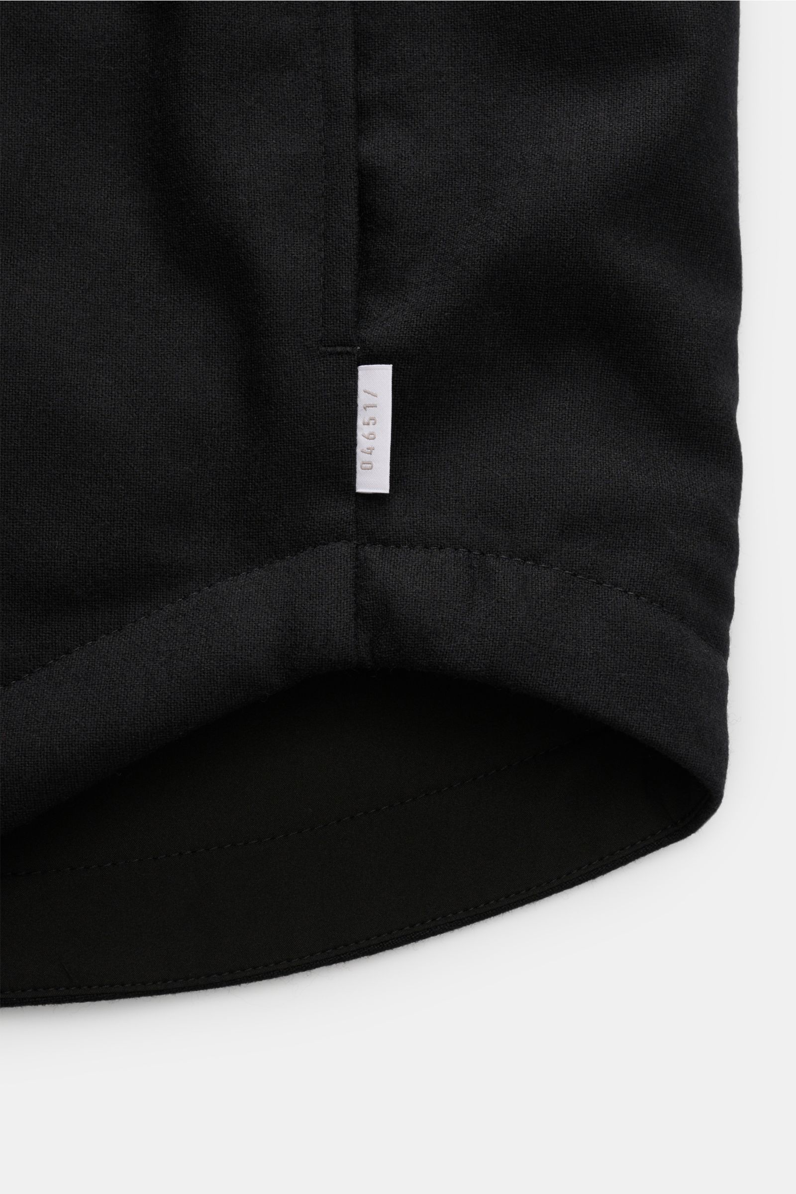 Close-up image of the rounded hem of the 04651/ A trip in a bag Reversible overshirt black, photographed from a bottom-up perspective. Features include a blend of wool, cashmere and premium-quality microfibre, reversible design, soft/smooth feel, slight s