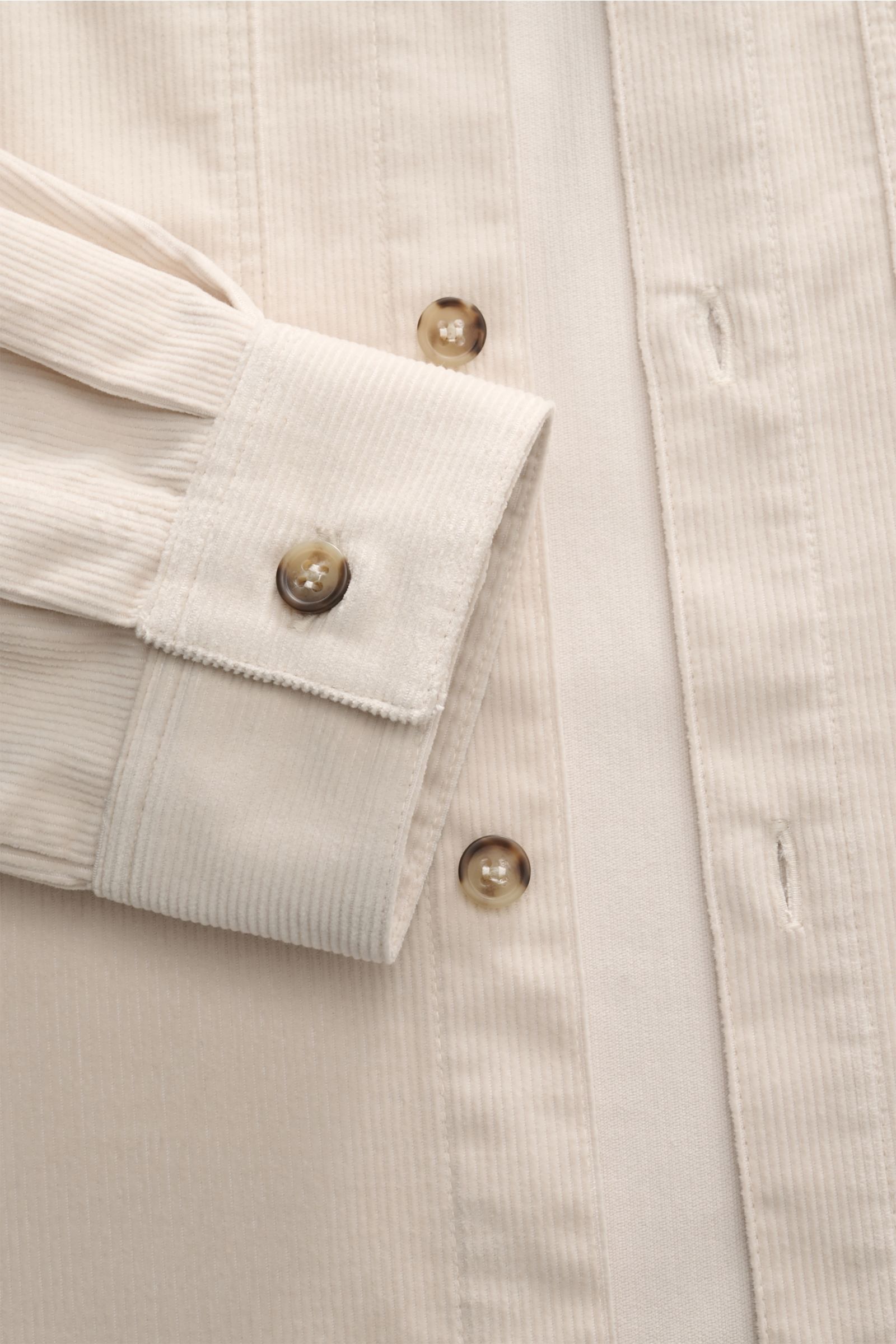 A close-up front view of the A.P.C. Overshirt 'Leon' creme in fine cotton corduroy, showing the slim fit soft fabric, Kent collar, tonal logo-stitching, French button placket, patch chest pockets, classic sport cuffs with buttons, and slightly rounded hem