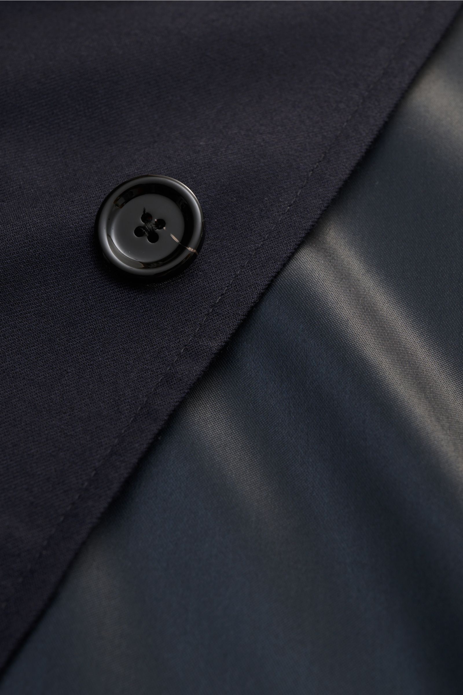 Close-up from above of a black button on the navy fabric and smooth lining of the Lardini Woll-Overshirt 'Aaansel' navy, made from lightweight elastic pure virgin wool with soft touch, regular fit, concealed five-button placket, flap chest pockets, side h