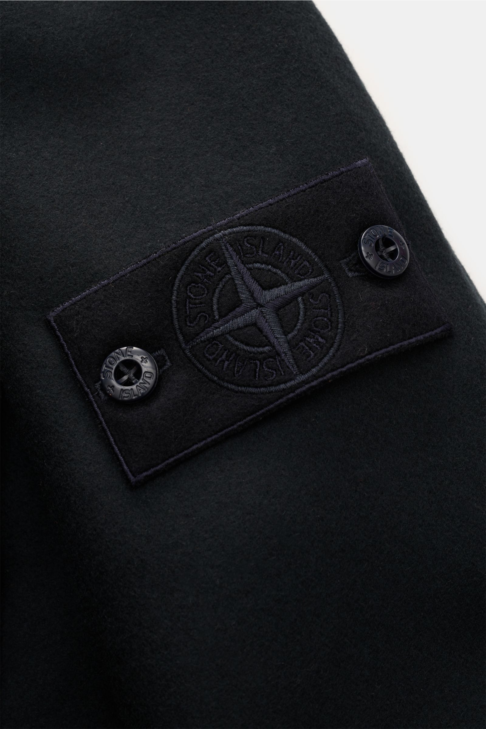 Alt tag (125 characters max):
Close-up of tonal Stone Island compass badge on sleeve of Stone Island Flannel overshirt 'Ghost Piece' dark navy, soft wool blend.

Description for context:
Pared down to the essentials but unmistakably STONE ISLAND: This 