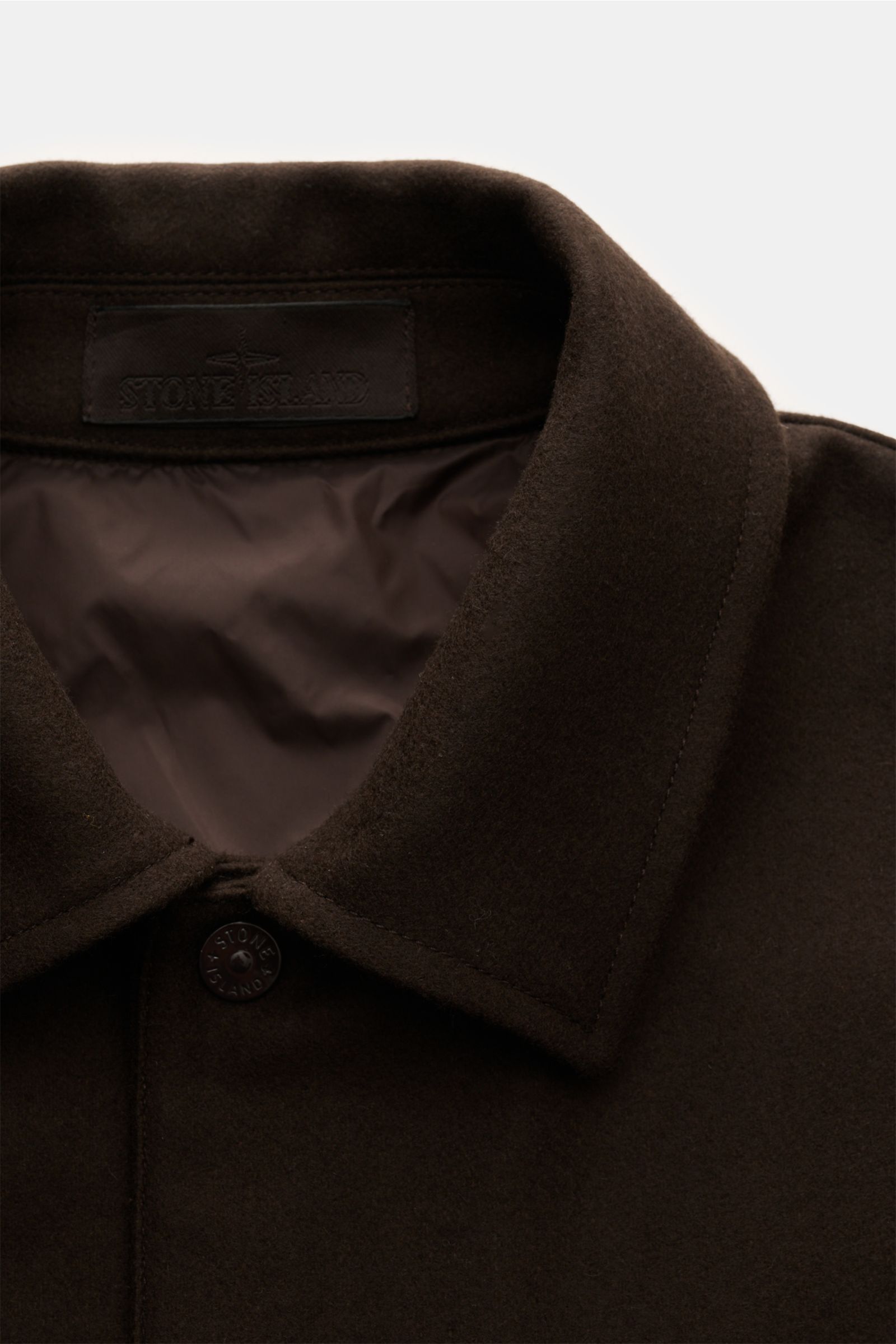 Close-up front view of Stone Island Flanell-Overshirt 'Ghost Piece' dunkelbraun collar and button, showing wool and microfiber fabric with soft texture and tonal details. Reduziert auf das Wesentliche und dabei unverkennbar STONE ISLAND: Dieses Overshi