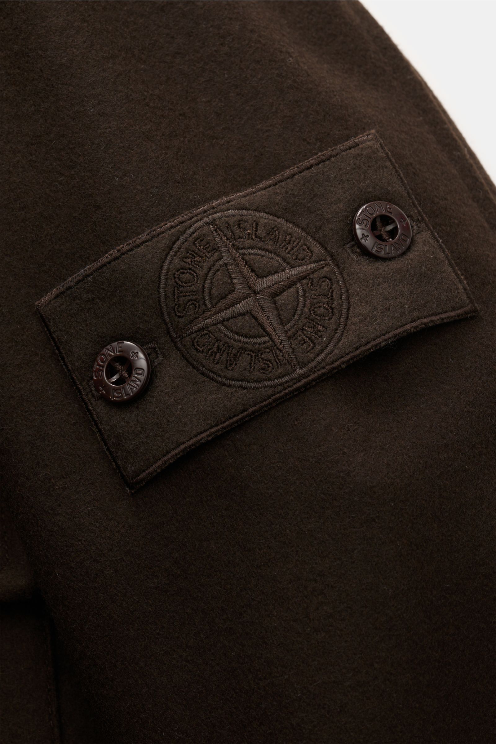 Close-up view of the tonal compass badge on the sleeve of the Stone Island Flanell-Overshirt 'Ghost Piece' dunkelbraun in dark brown wool blend.

Reduziert auf das Wesentliche und dabei unverkennbar STONE ISLAND: Dieses Overshirt aus der 'Ghost Collect