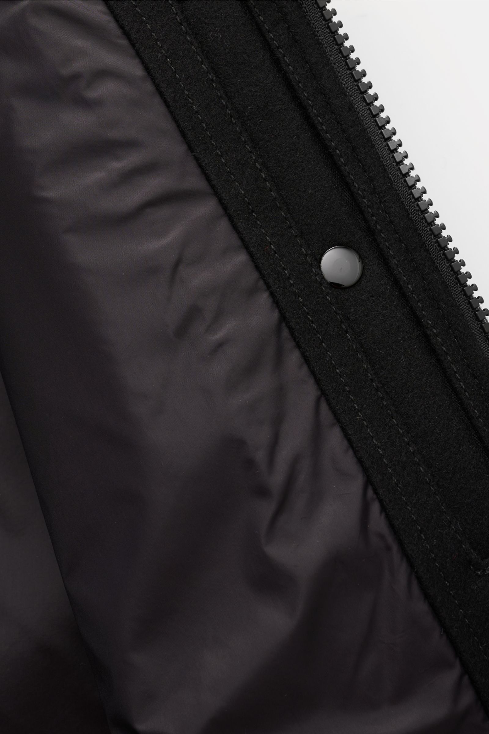 Nahaufnahme des glatten Innenfutters und gefilzten Woll-Mix-Stoffes vom Stone Island Overshirt 'Ghost Piece' schwarz, Innenansicht zeigt robusten Zwei-Wege-Reißverschluss und Druckknopf.