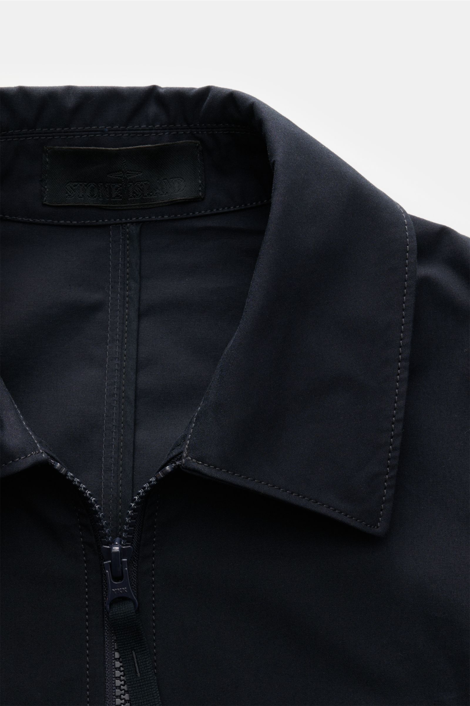 Close-up front view of Stone Island Overshirt 'Weather Proof Cotton Canvas Ghost Piece' navy collar and two-way zip, made of soft, wind and water repellent cotton canvas with tonal logo badge.

Description: Get the best casual look for autumn with the 