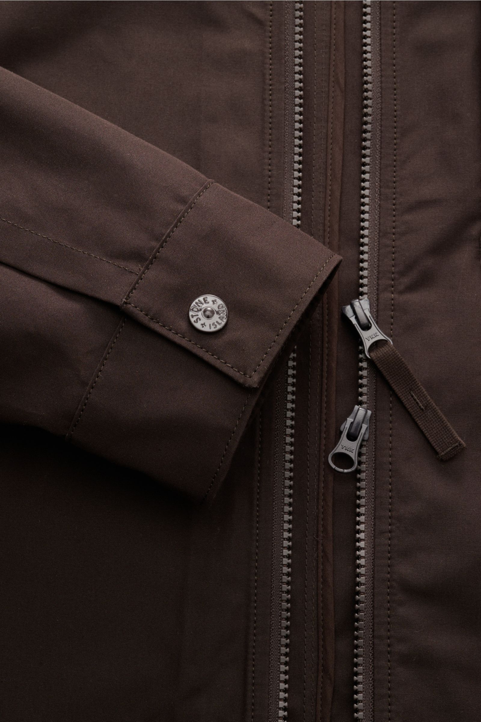 Stone Island Overshirt 'Weather Proof Cotton Canvas Ghost Piece' dunkelbraun, Detailaufnahme von Ärmel mit Druckknopf und Zwei-Wege-Reißverschluss.