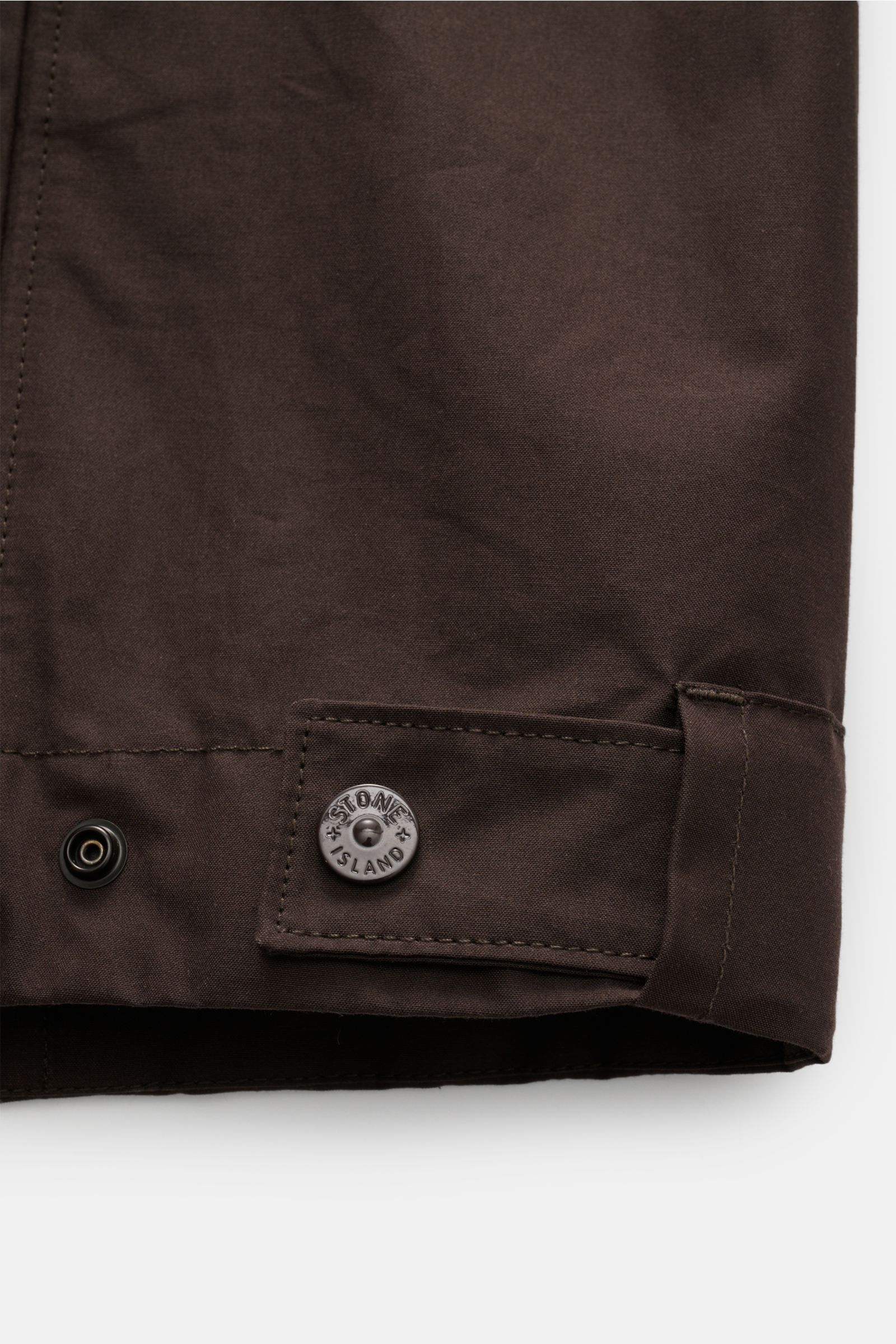 Stone Island Overshirt 'Weather Proof Cotton Canvas Ghost Piece' dunkelbraun, Nahaufnahme Ärmelsaum mit Druckknopf und Logo-Badge, Baumwoll-Canvas, wind- und wasserabweisend.