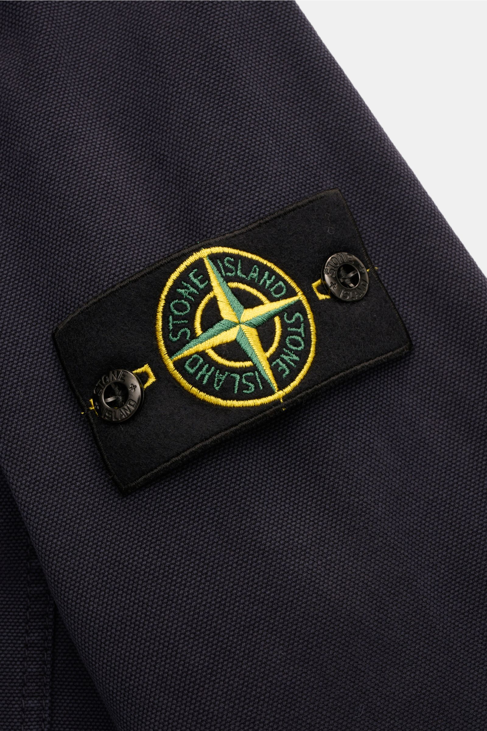Nahaufnahme des Kompass-Badges am Ärmel des Stone Island Overshirt 'Organic Panama' navy aus reiner Baumwolle mit weichem Griff.