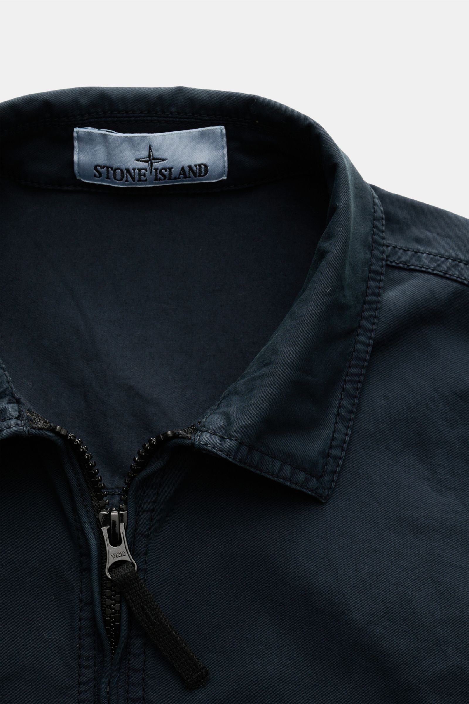 Nahaufnahme aus schräger Perspektive des Stone Island Overshirt navy mit Umlegekragen, Zwei-Wege-Reißverschluss, Twill aus reiner Baumwolle, slim fit, weichem Griff, leichter Qualität, garment dyed, Brusttasche mit Zipper, regulierbaren Ärmelabschlüssen m