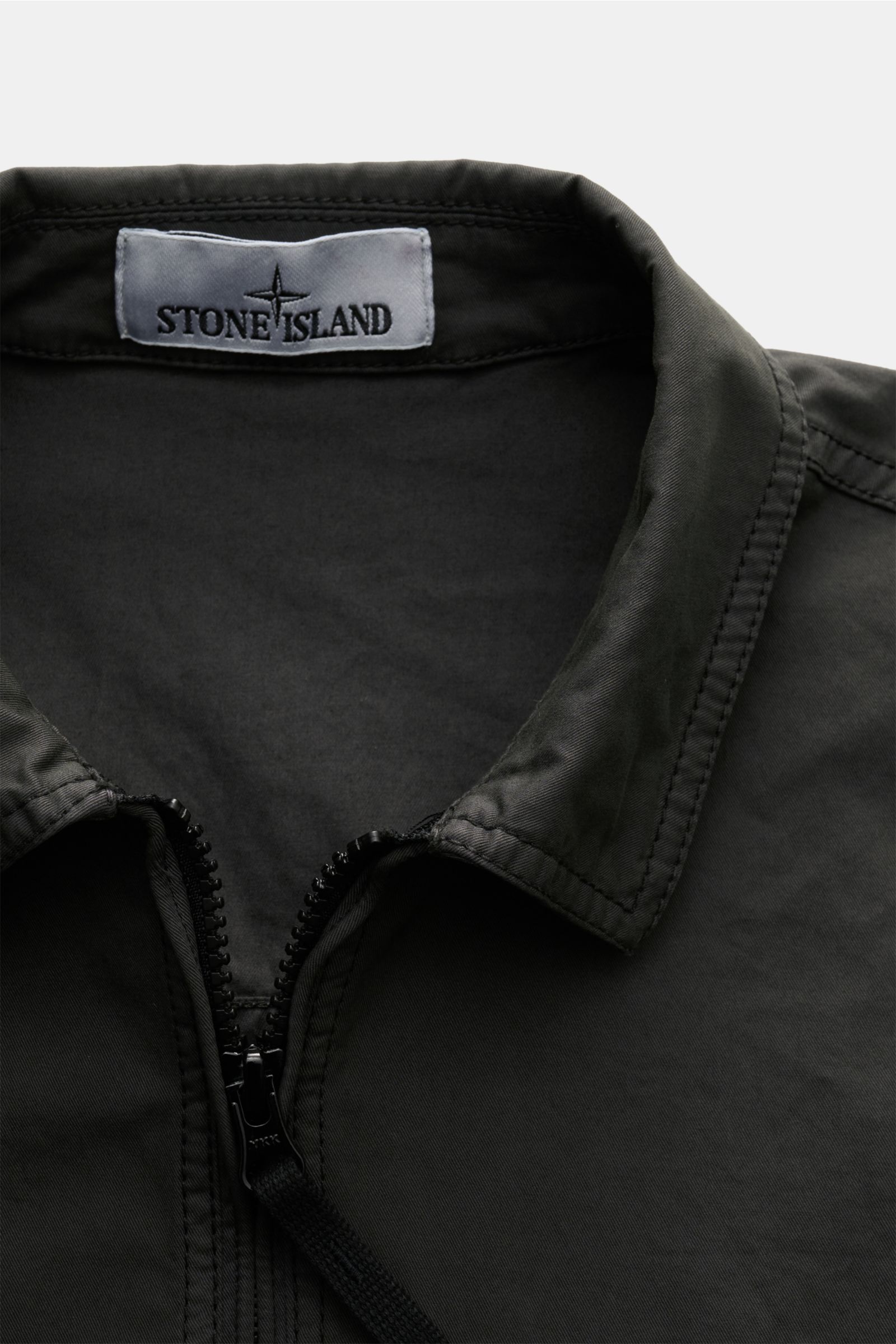 Stone Island Overshirt graugrün close-up from the front showing twill cotton, elastic, soft, lightweight, garment dyed, slim fit, two-way zipper, collar, chest zip pocket, compass badge on sleeve, adjustable cuffs with snap buttons.