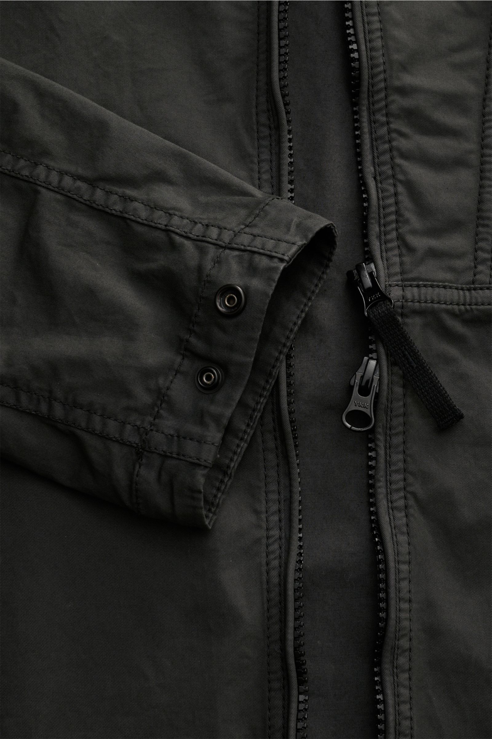 Close-up front view of Stone Island Overshirt graugrün showing twill cotton fabric with elastic, soft, lightweight garment-dyed material, slim fit, two-way zipper, fold-down collar, zippered chest pocket, typical compass badge on sleeve, and adjustable cu